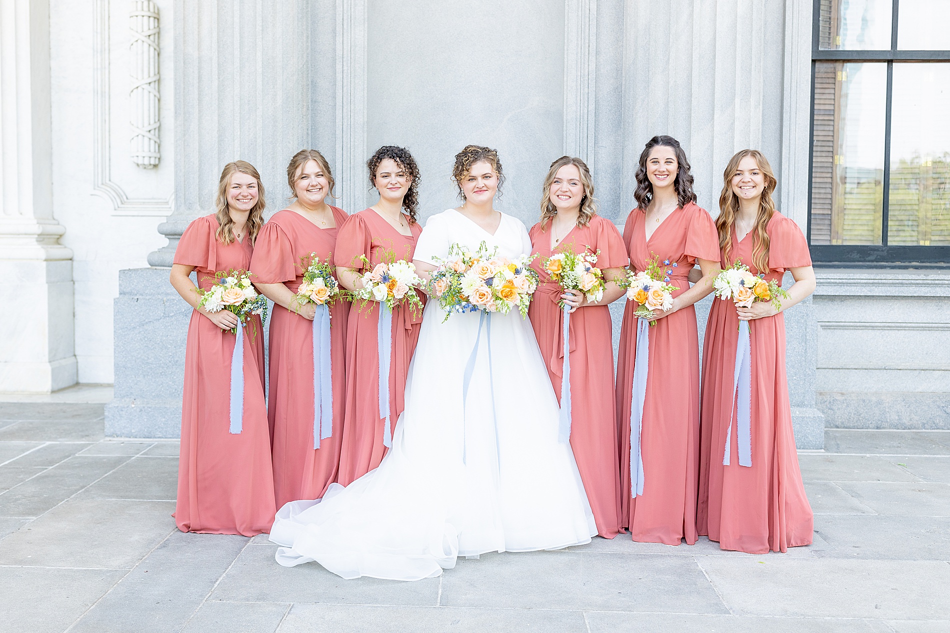 bride with bridesmaids in coral dresses