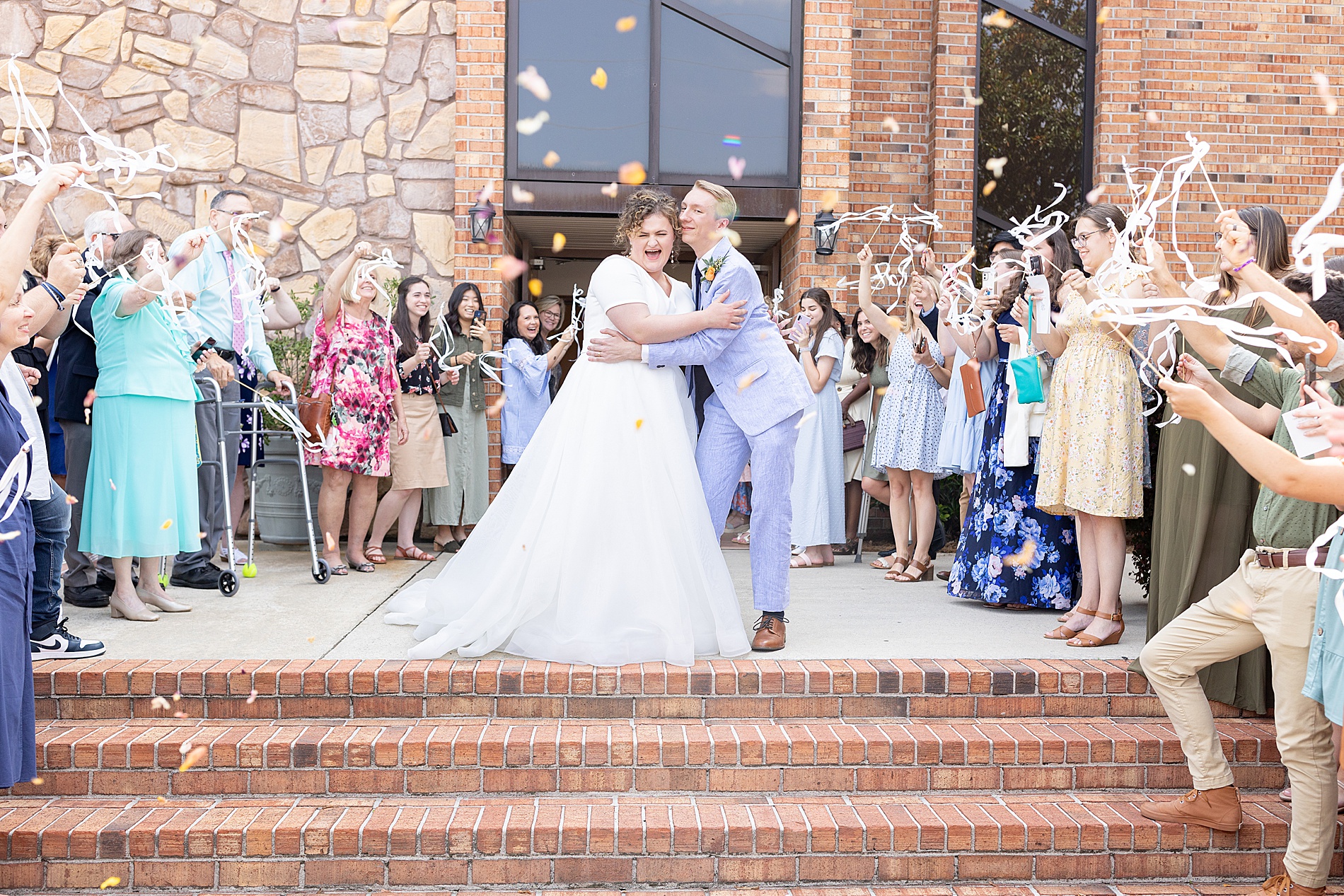wedding guests throw confetti as newlyweds exit church