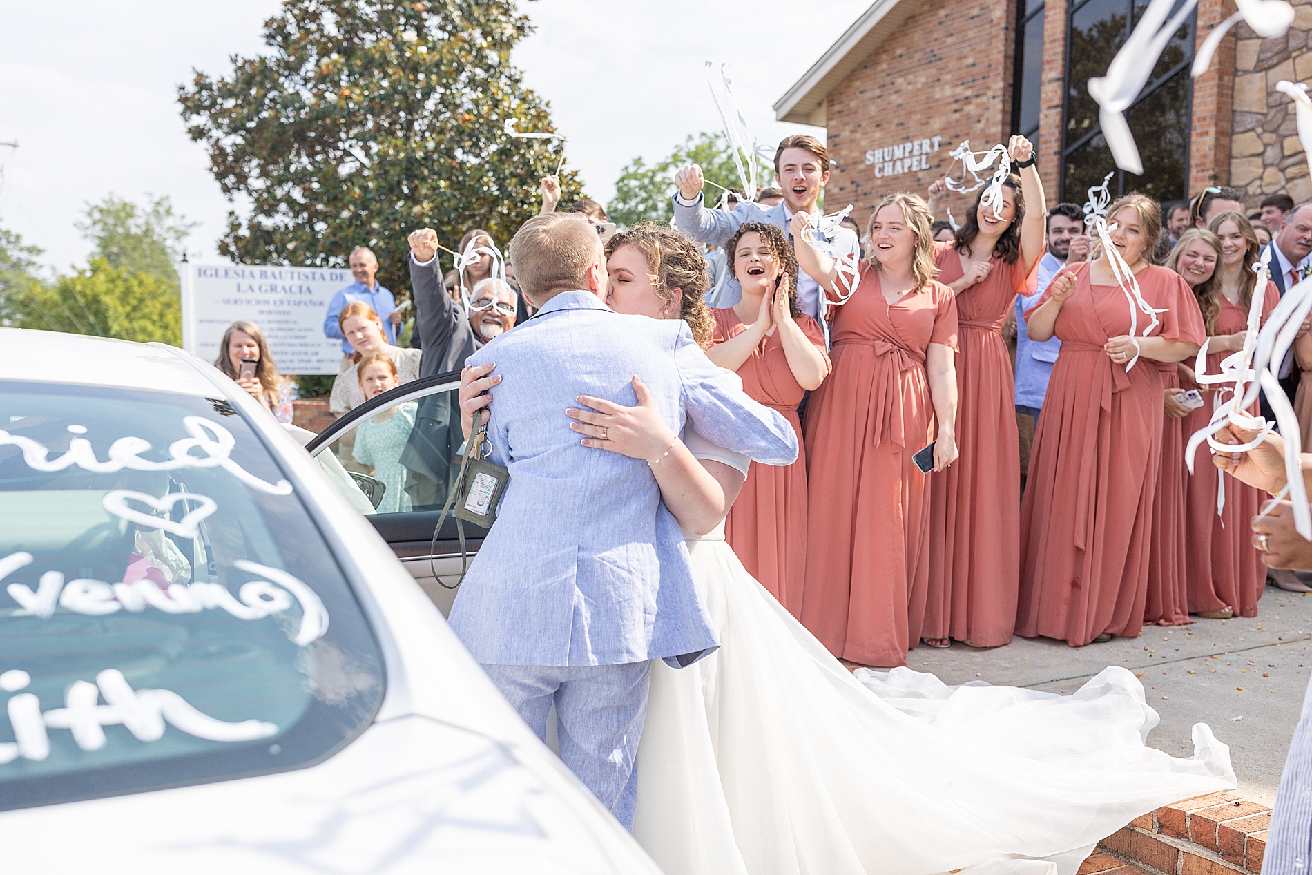 bride and groom kiss as they get in car