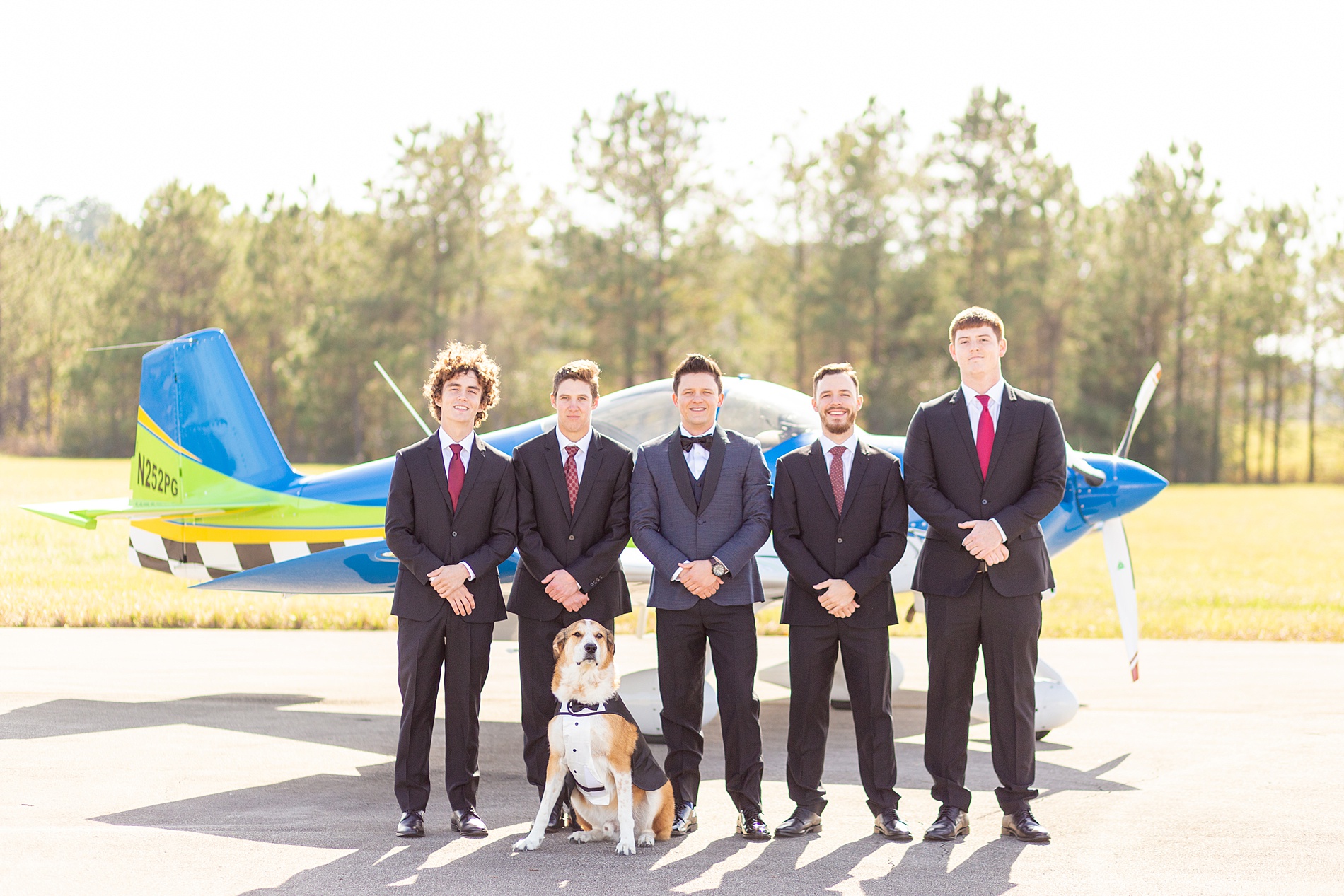 groom and groomsmen in front of airplane