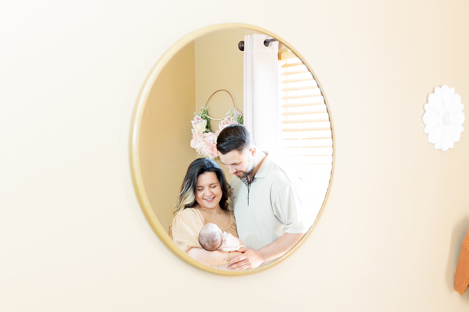 reflection in mirror of parents holding newborn girl 