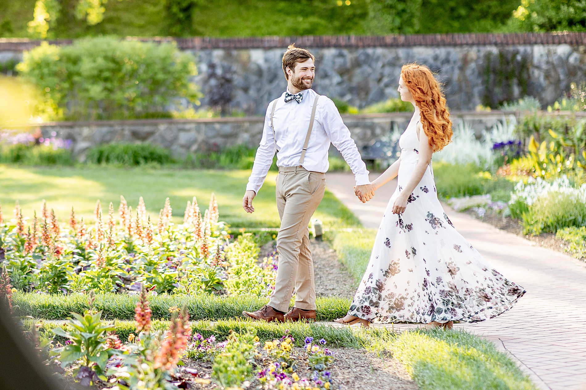 couple hold hands as they walk through the garden