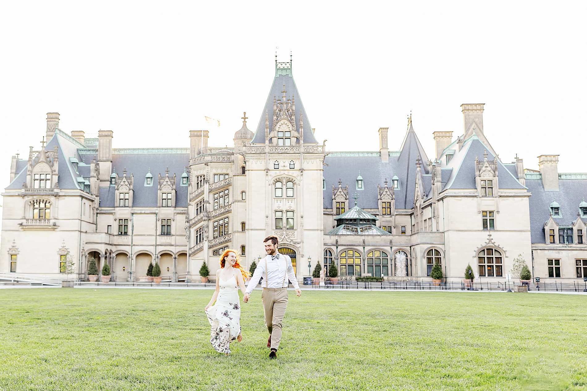 timeless engagement photos of couple running in front beautiful mansion at Biltmore Estate  