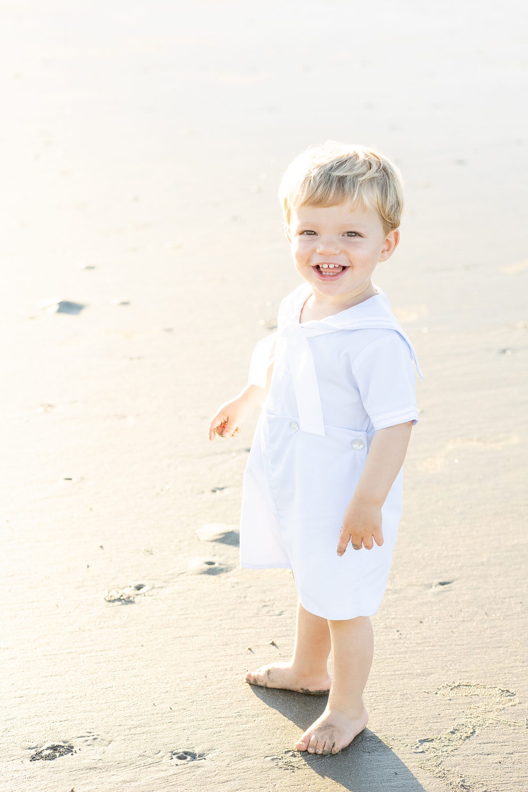 little boy in white outfit on the beach