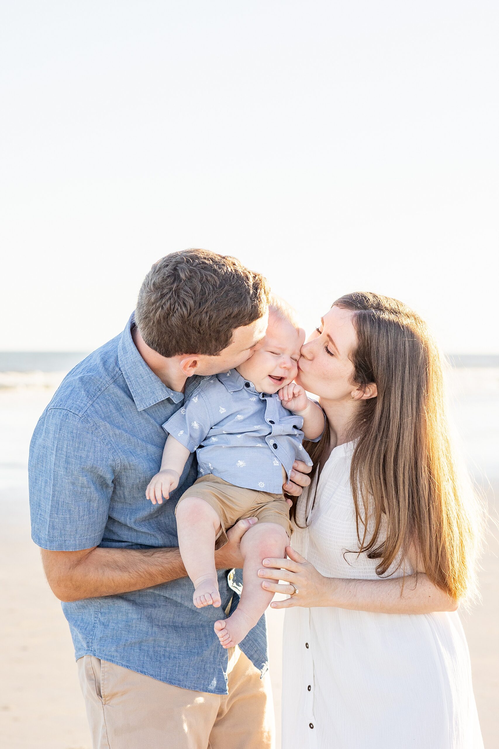 parents kiss their son on the cheek