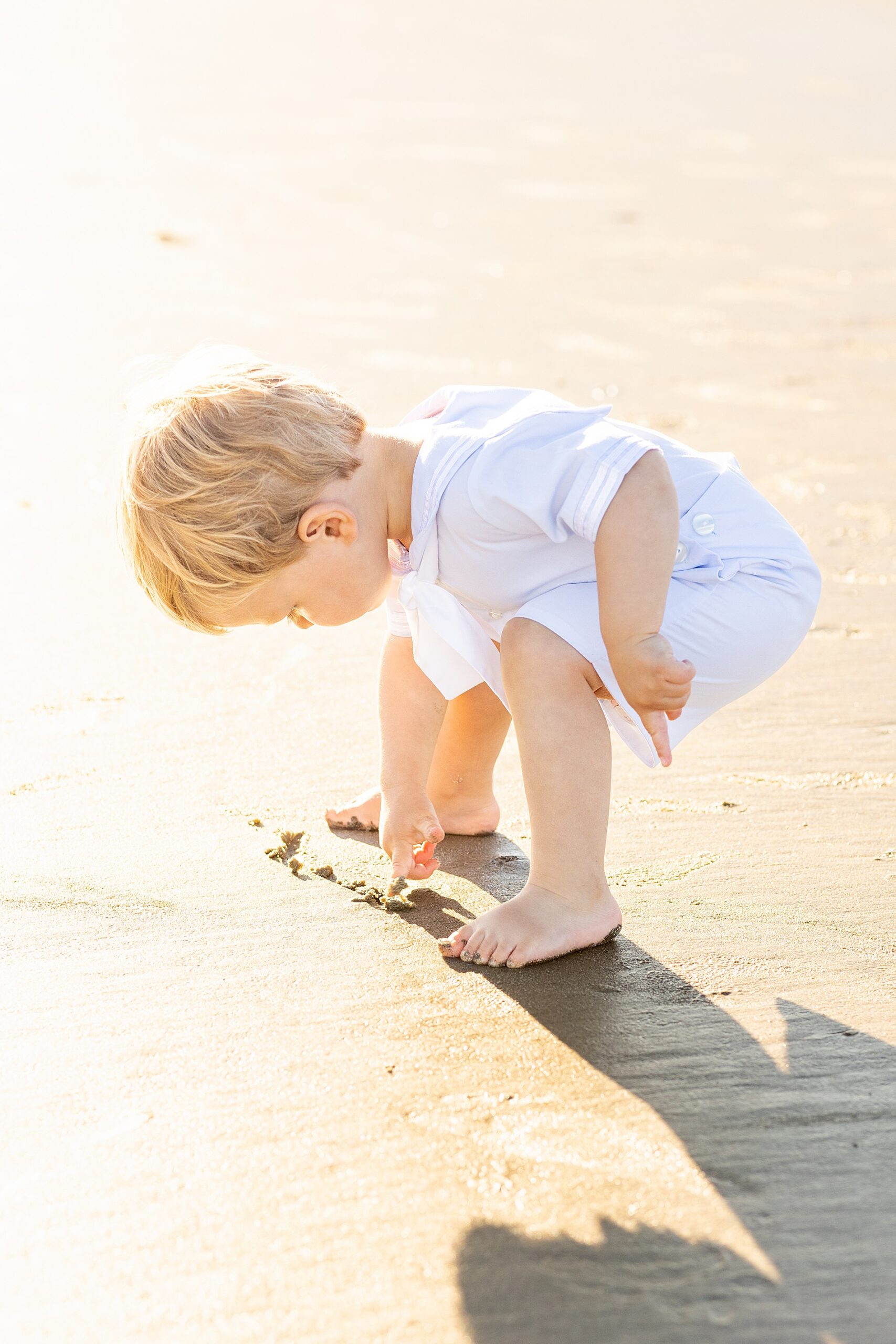 little boy digs in the sand