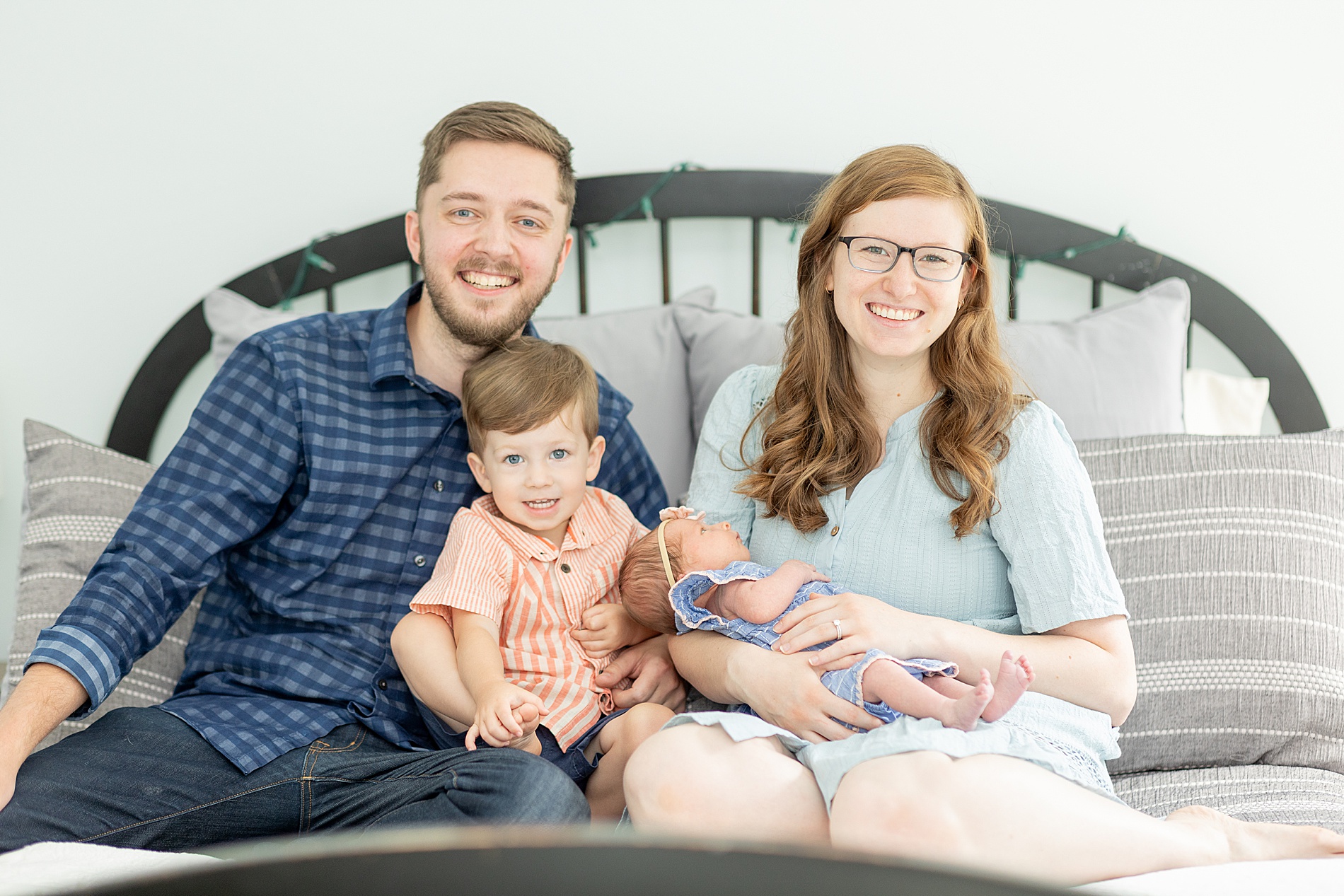 family of four sit on bed during In-Home Lifestyle Newborn Session