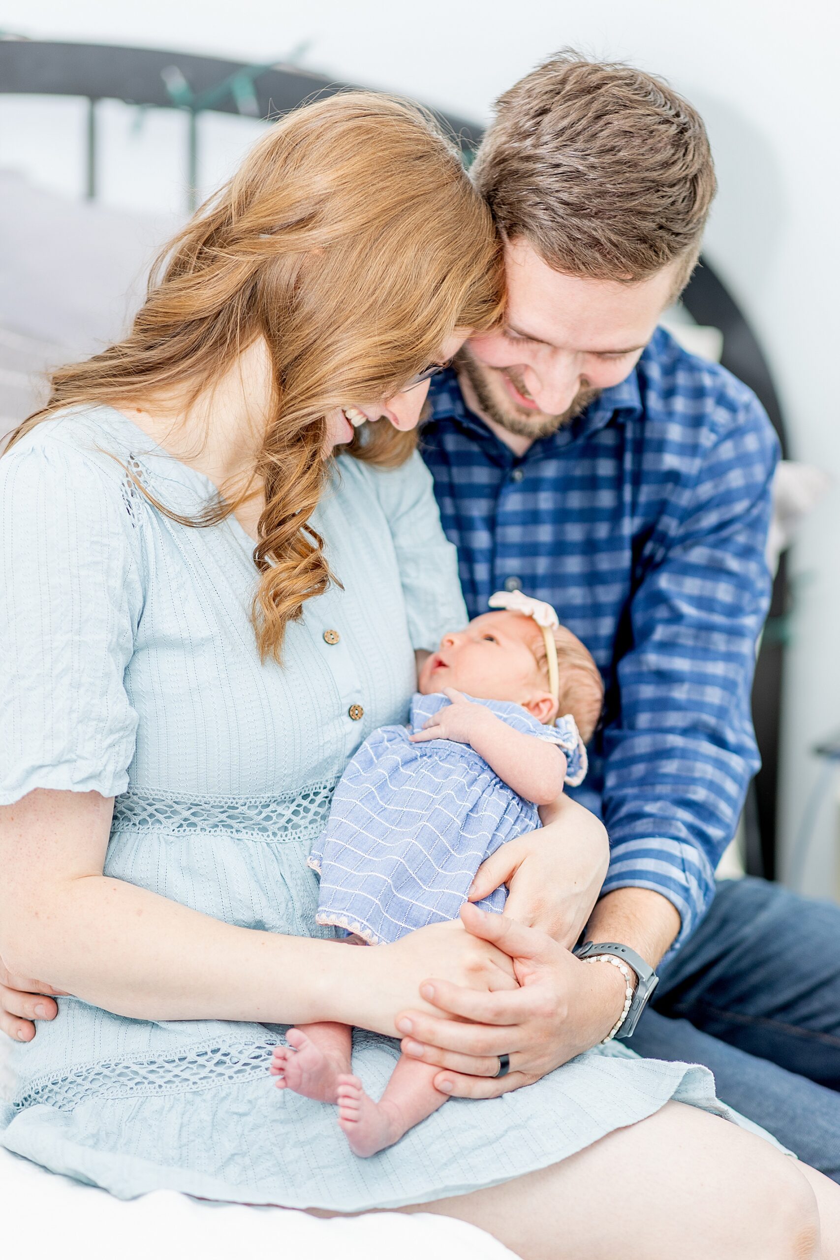 parents hold their newborn and look down at her