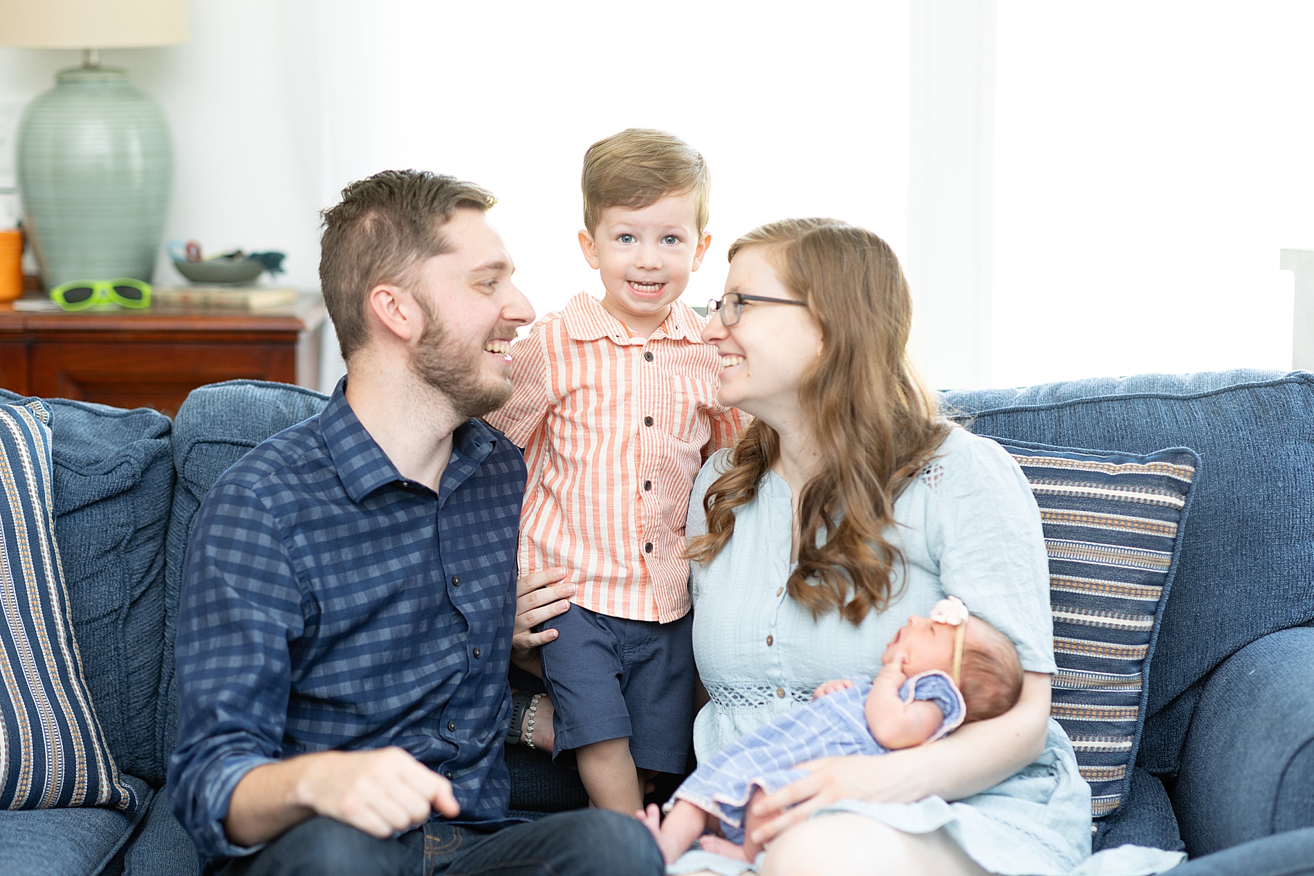 family of four sit together on the couch during In-Home Lifestyle Newborn Session