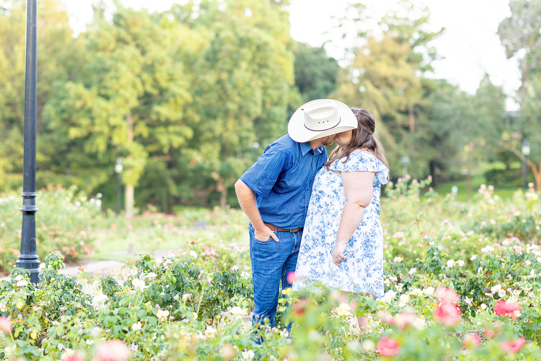 engaged couple kiss in field of flowers