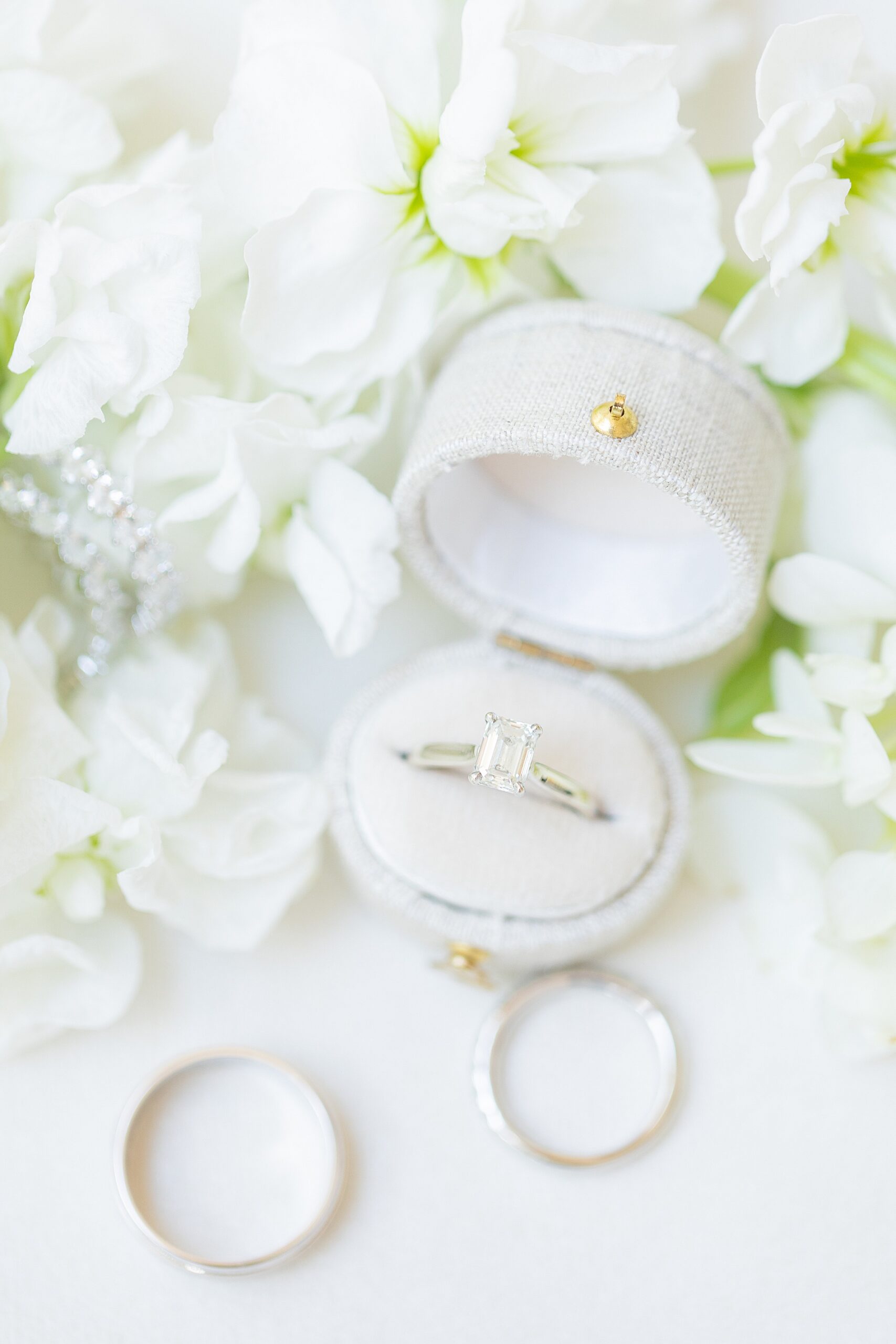 wedding rings in ring box surrounded by white flowers