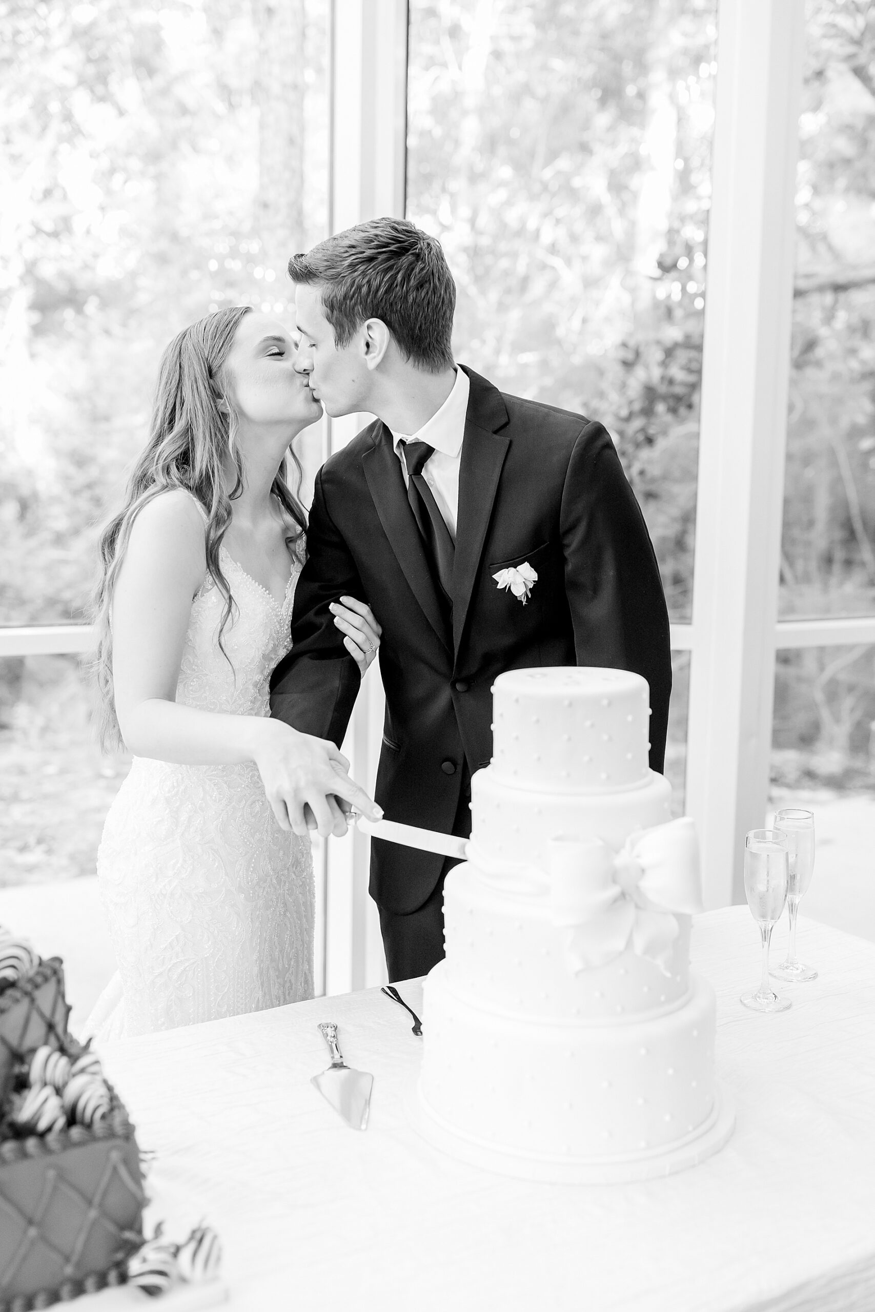 newlyweds kiss as they cut wedding cake