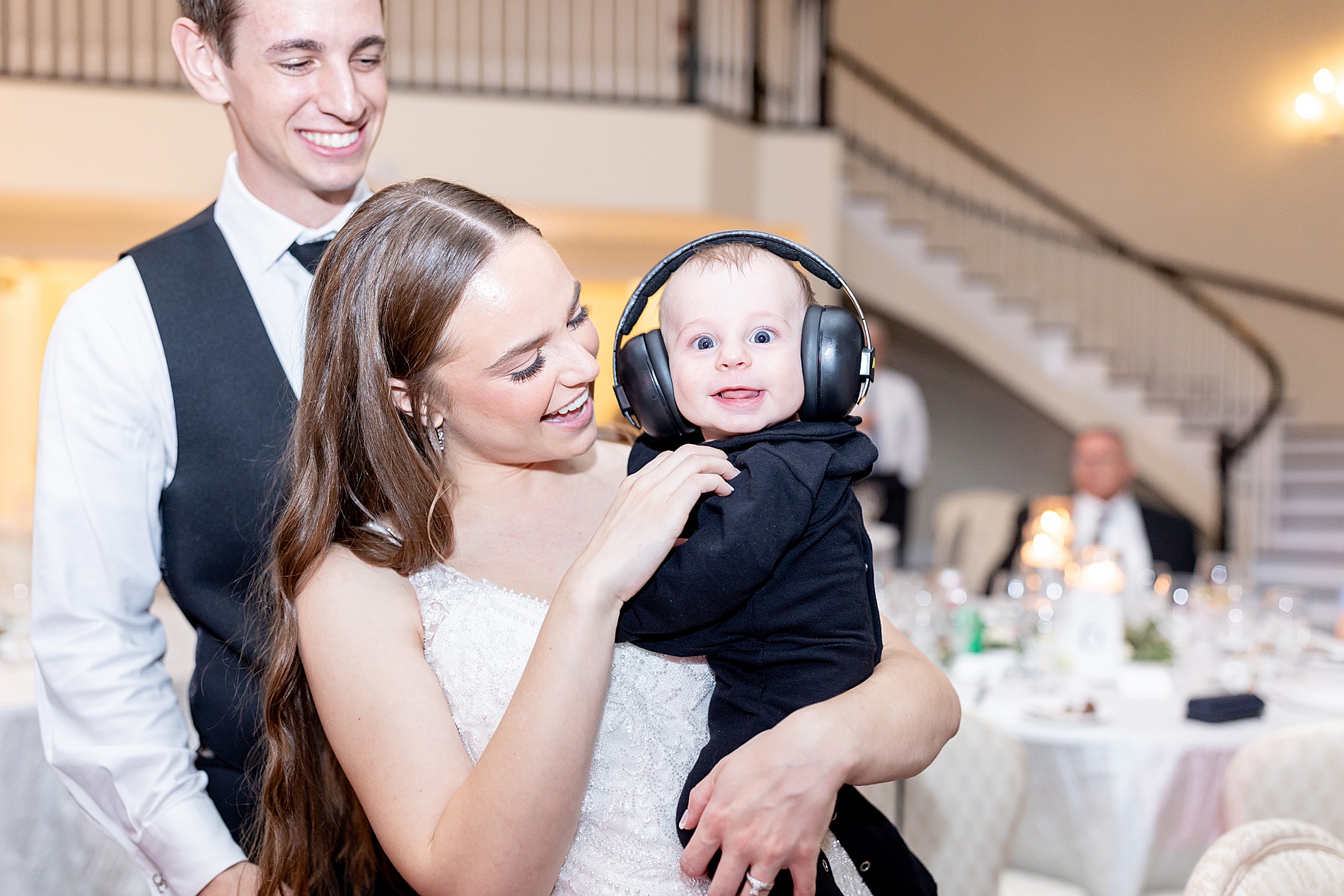 bride holds baby with headphones on