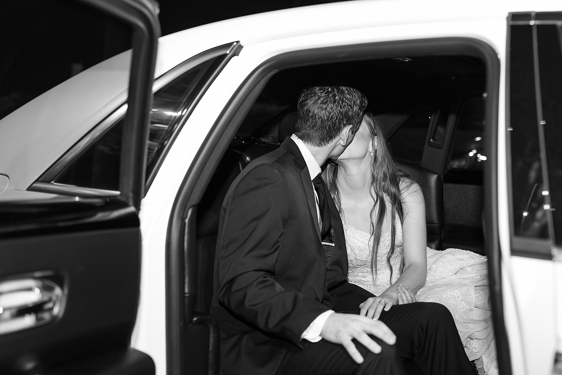 bride and groom kiss in getaway car