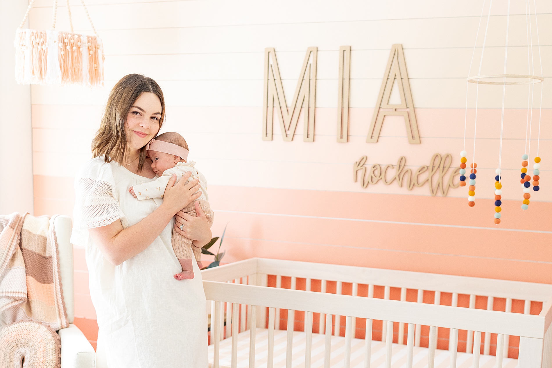 mom holds baby girl in pink nursery