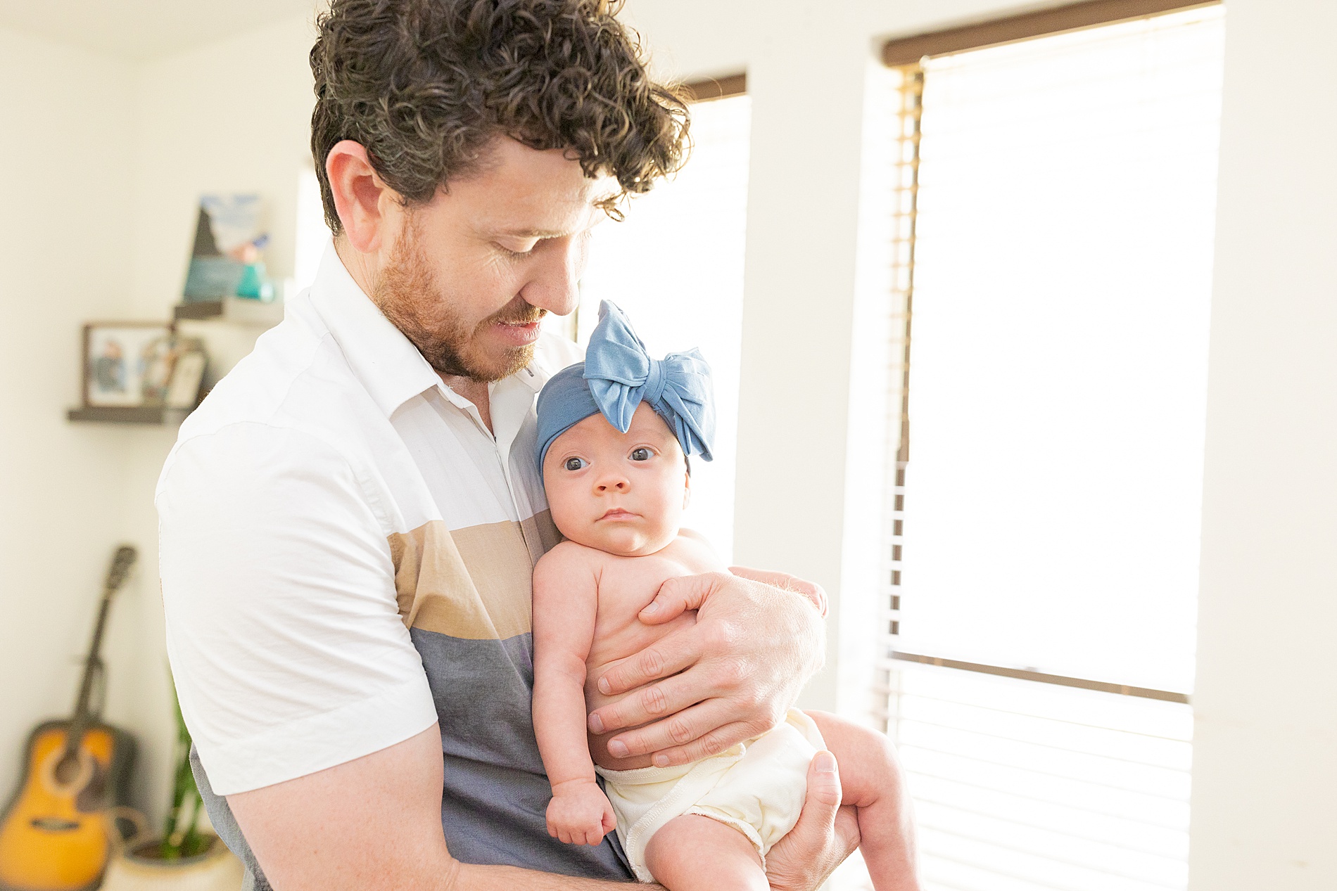 dad holds newborn girl in blue headband