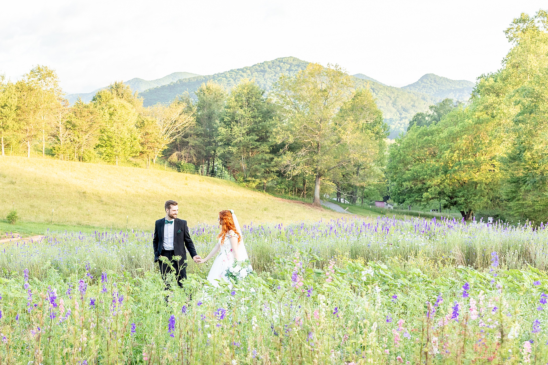 bride and groom walk through tall grass