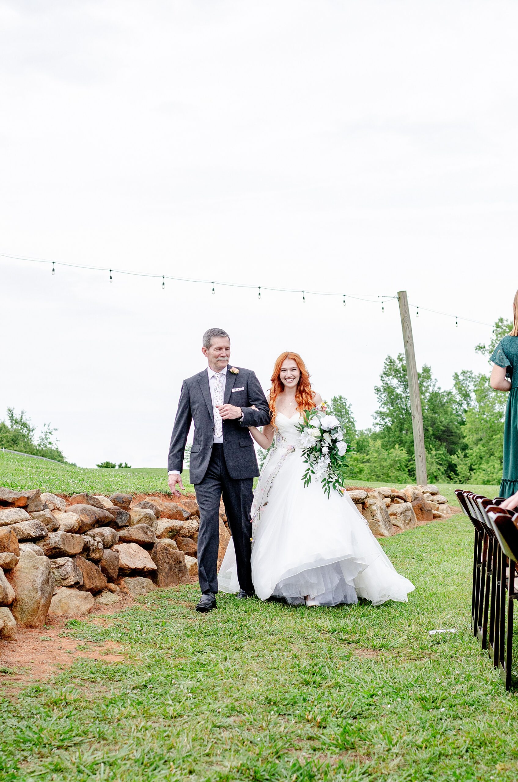 bride walks towards ceremony wtih father