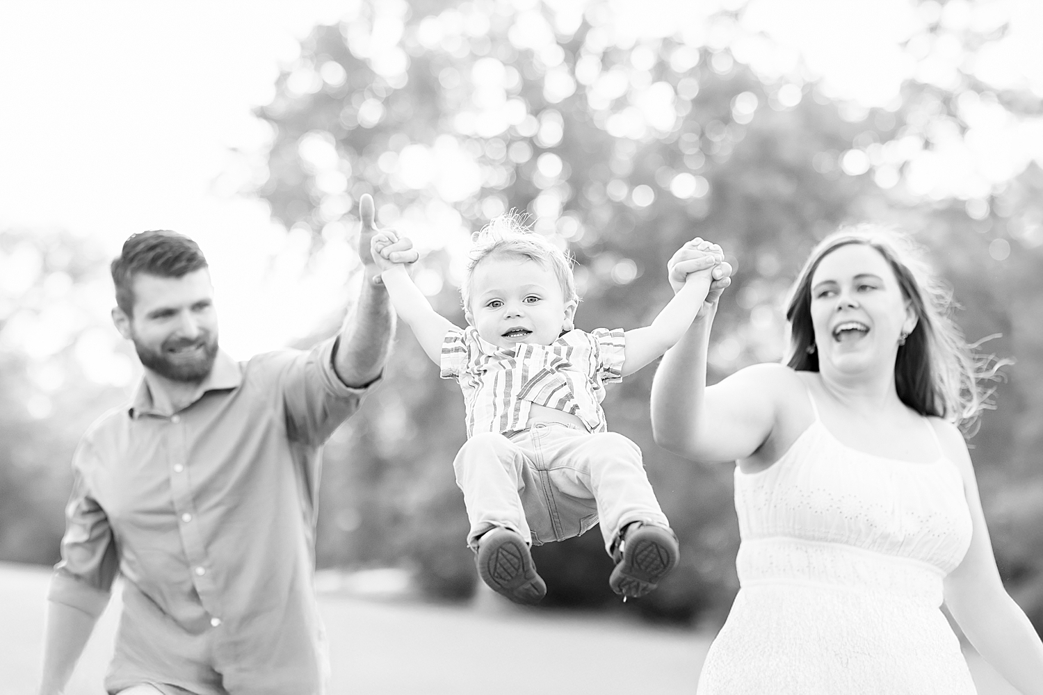 Timeless family portraits of parents swinging their son as they walk together