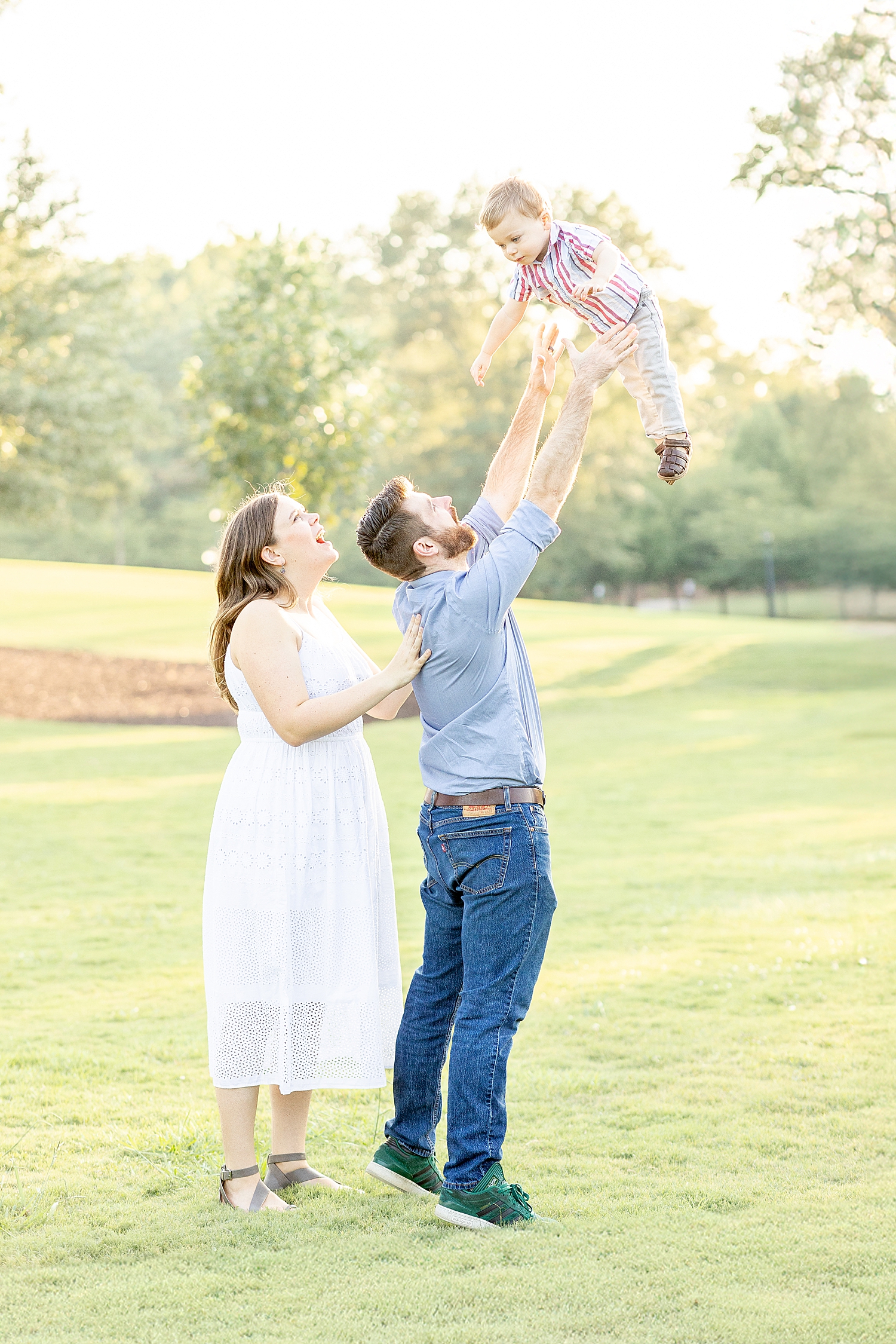 parents hold their son up in the air for candid portriats