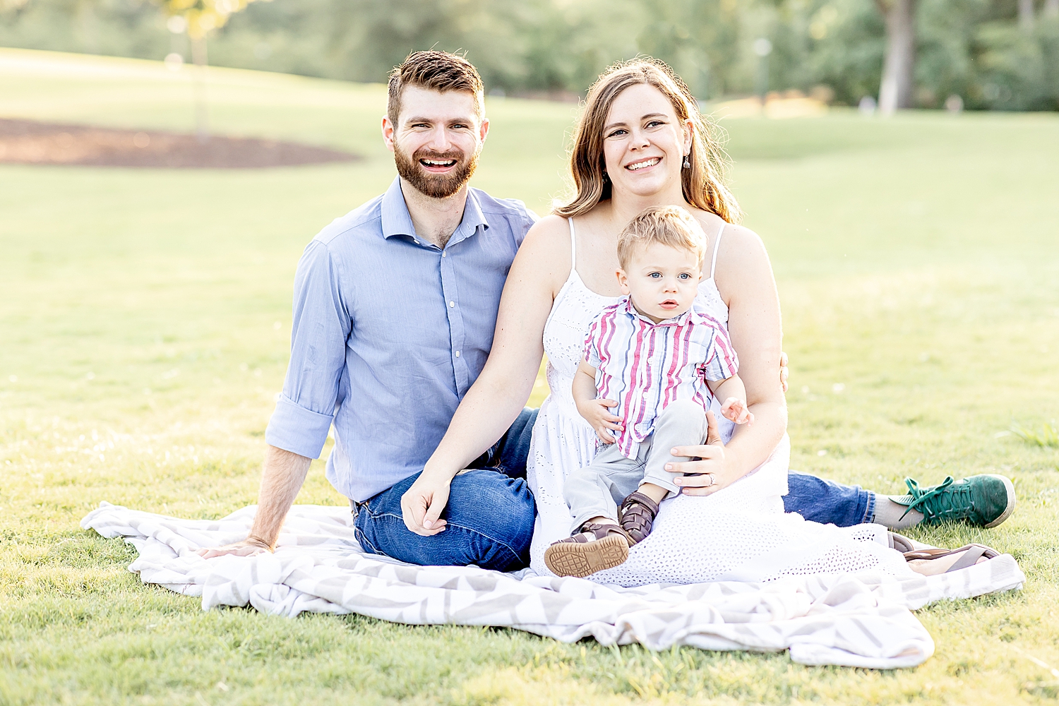 family sits on blanket in park