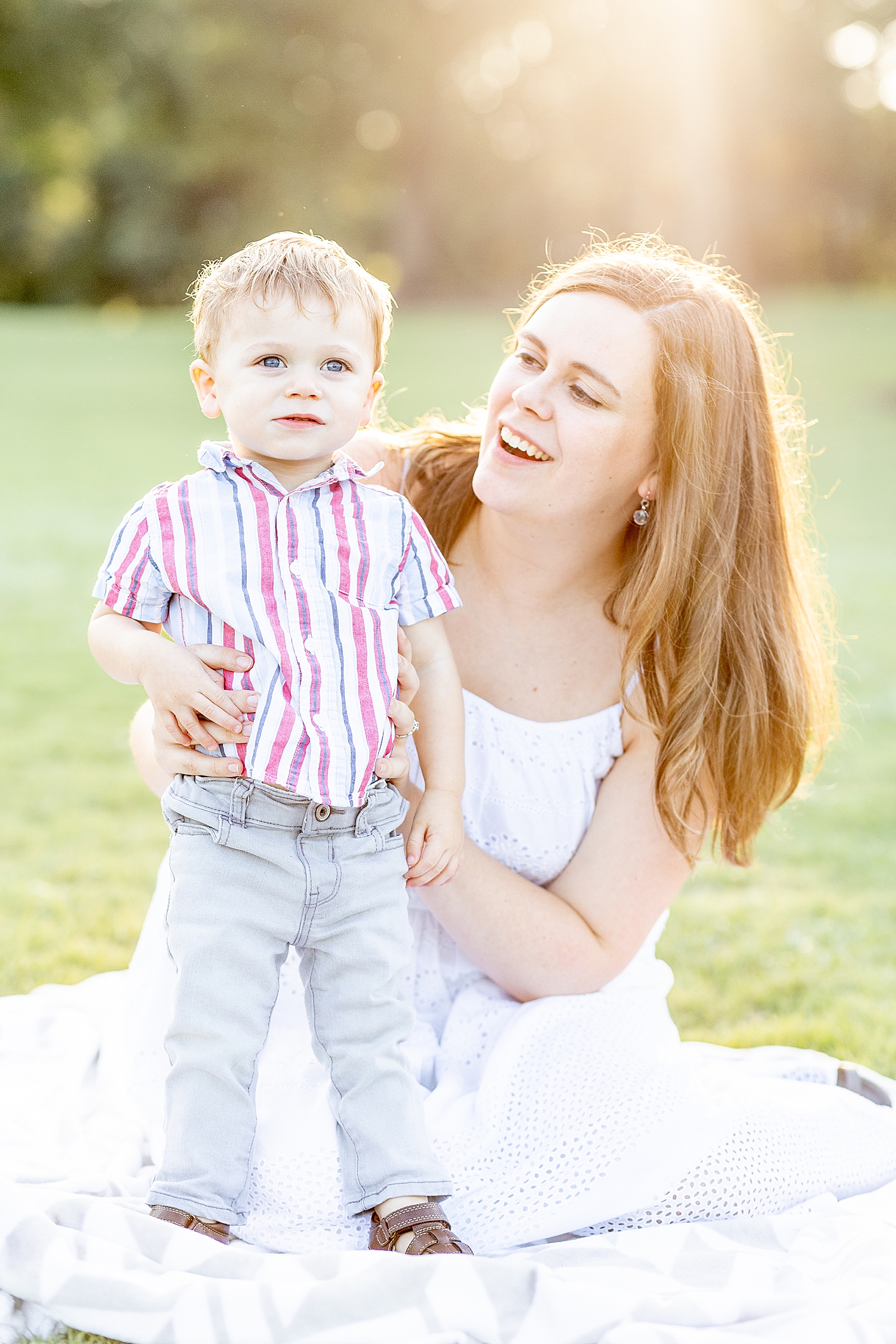 mom sits on blanket with her son in park