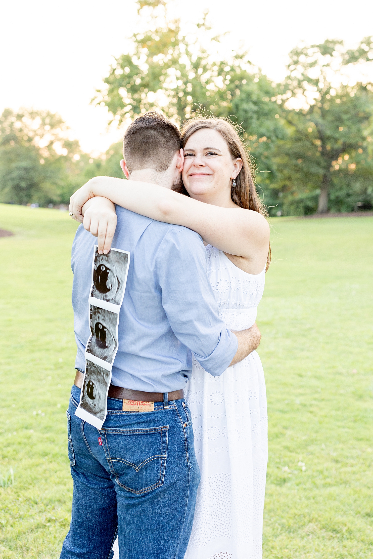 parents hug as mom holds ultrasound photo