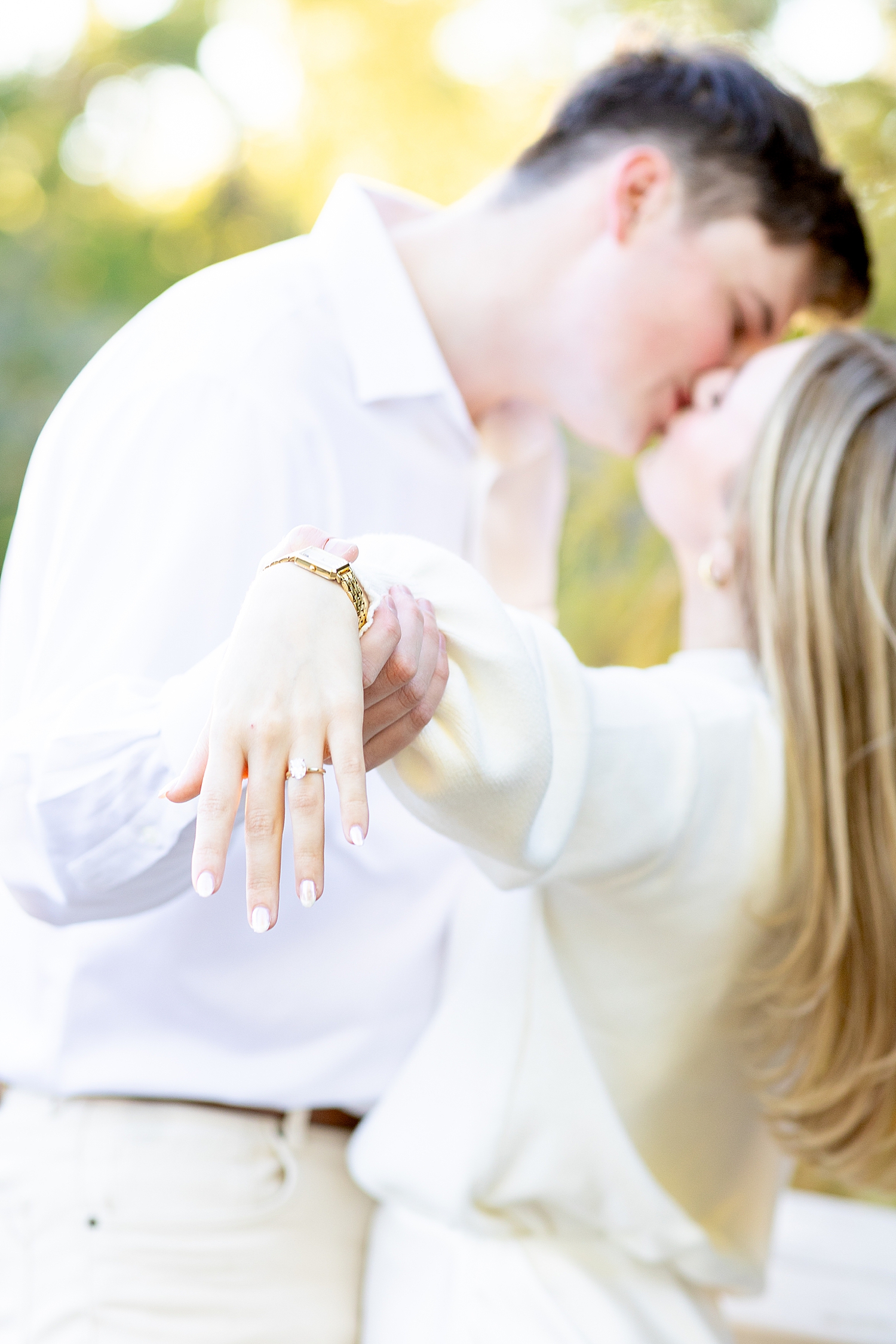 couple kiss and show off engagement ring