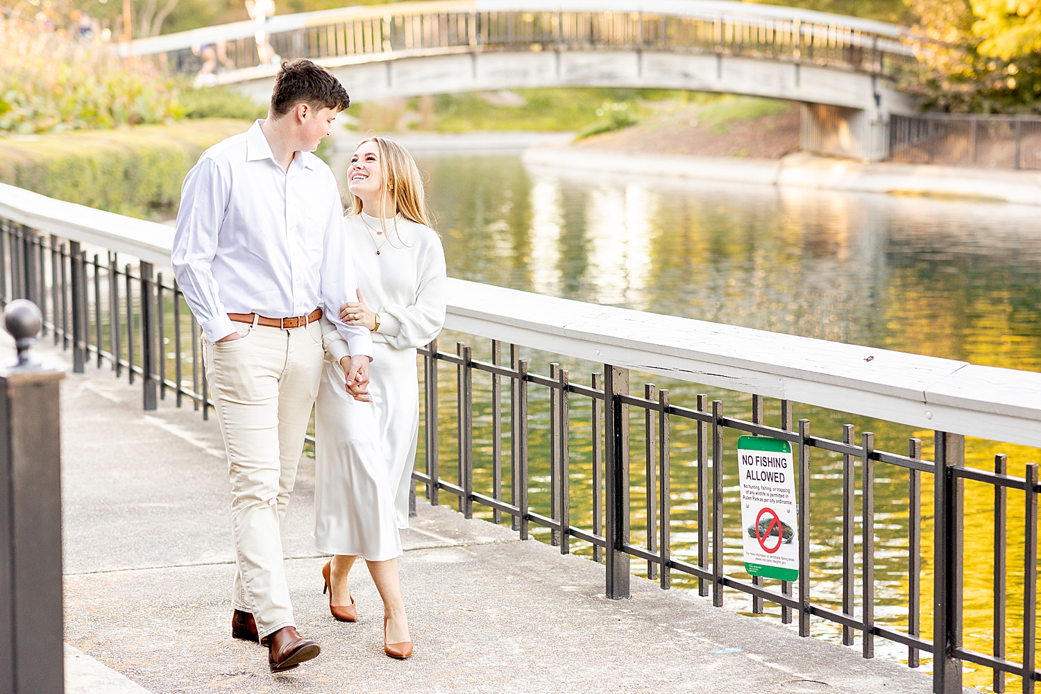 newly engaged couple walk together across bridge