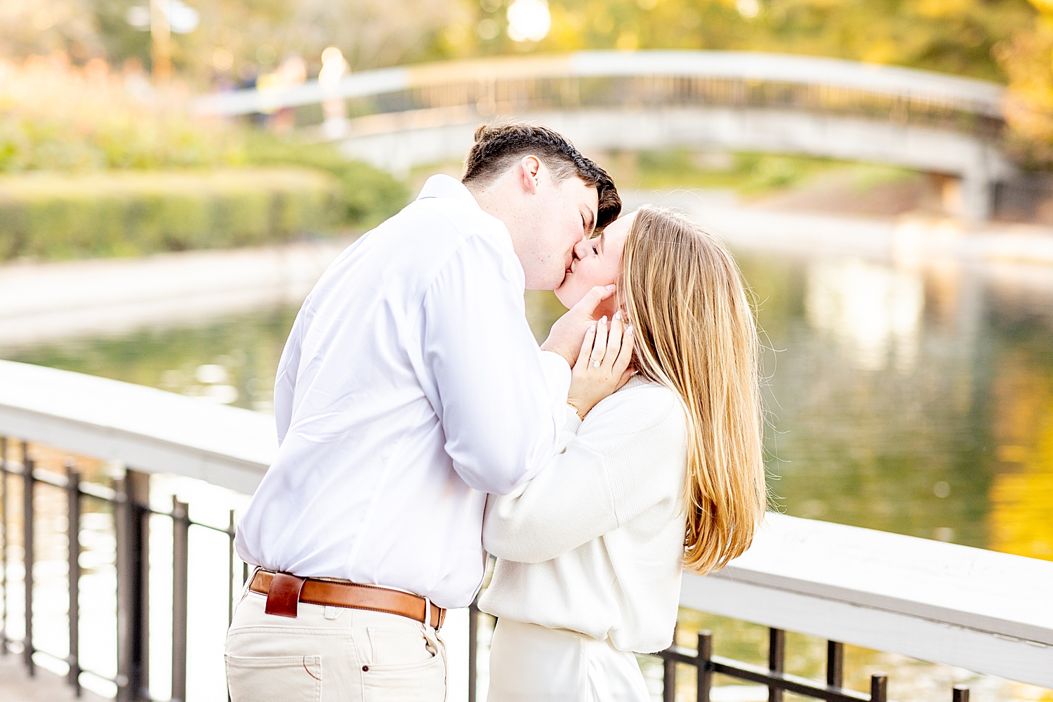 couple kiss on bridge overlooking water