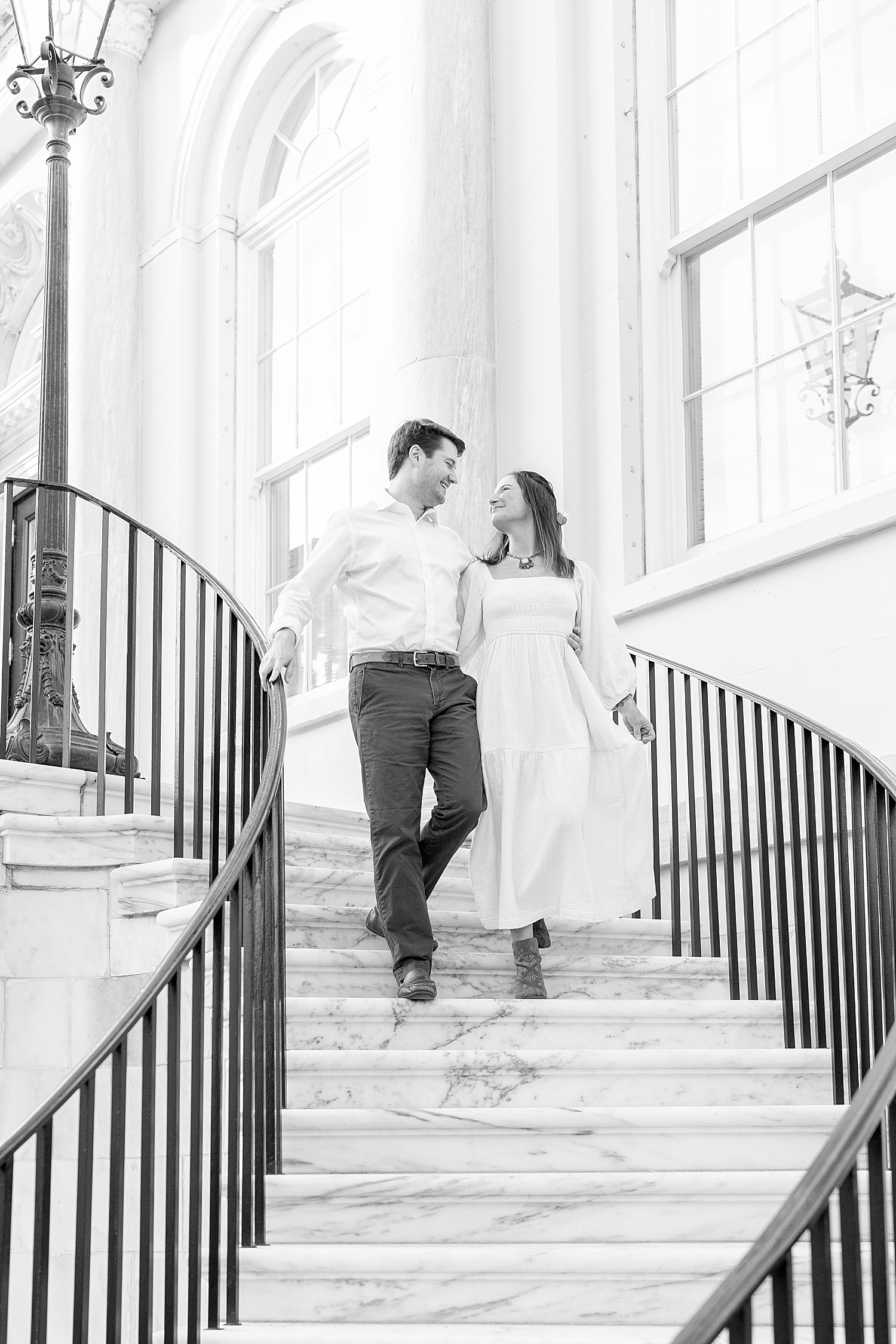 engaged couple walk down spiral staircase