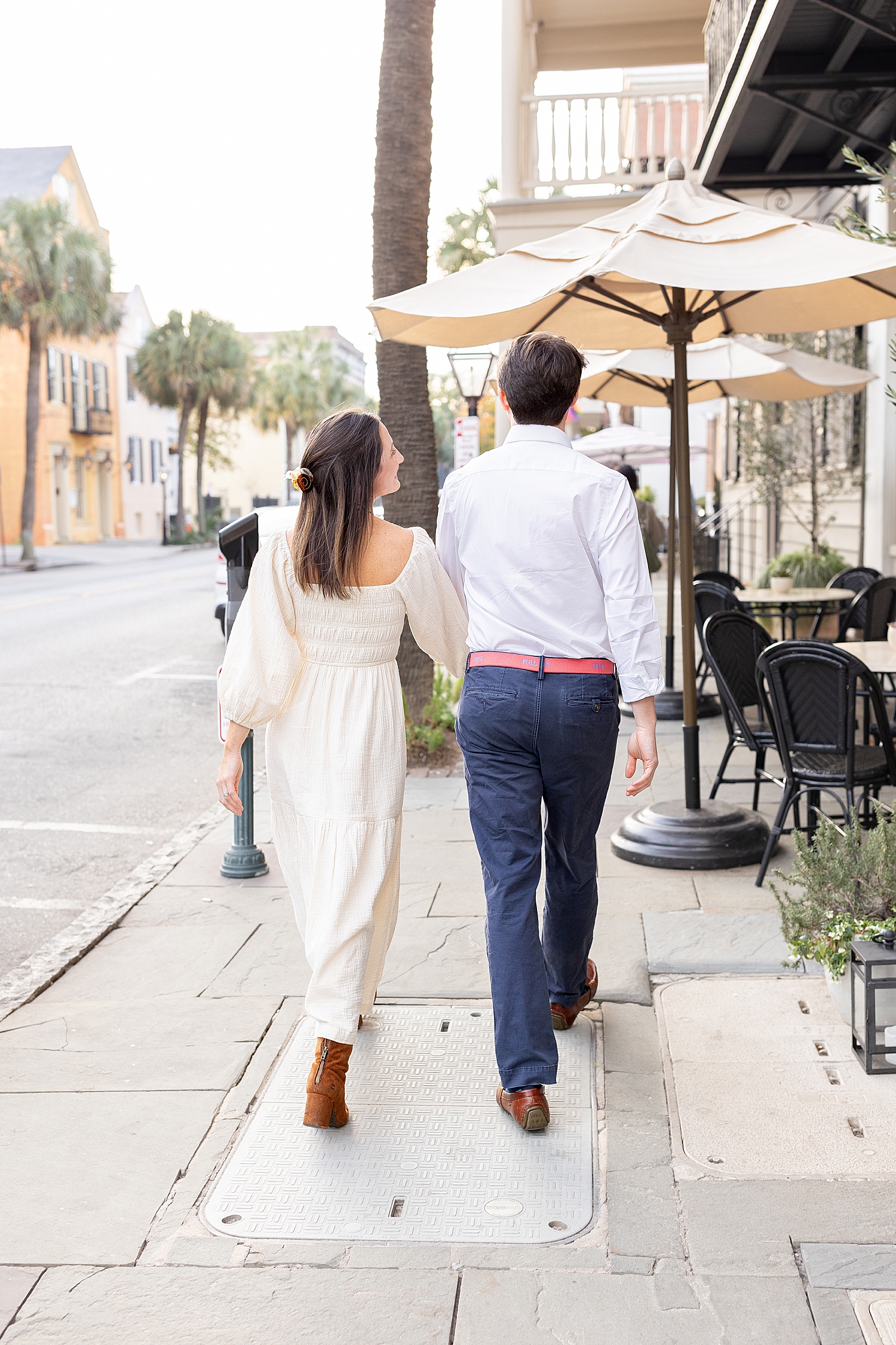 engaged couple hold hands as they walk down Charleston street