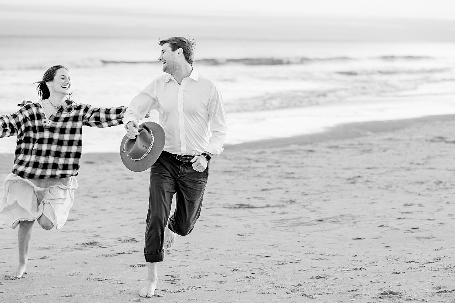 couple run and laugh together on beach