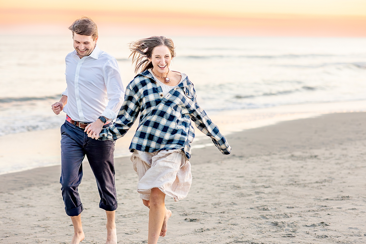 couple run together holding hands on Folly Beach