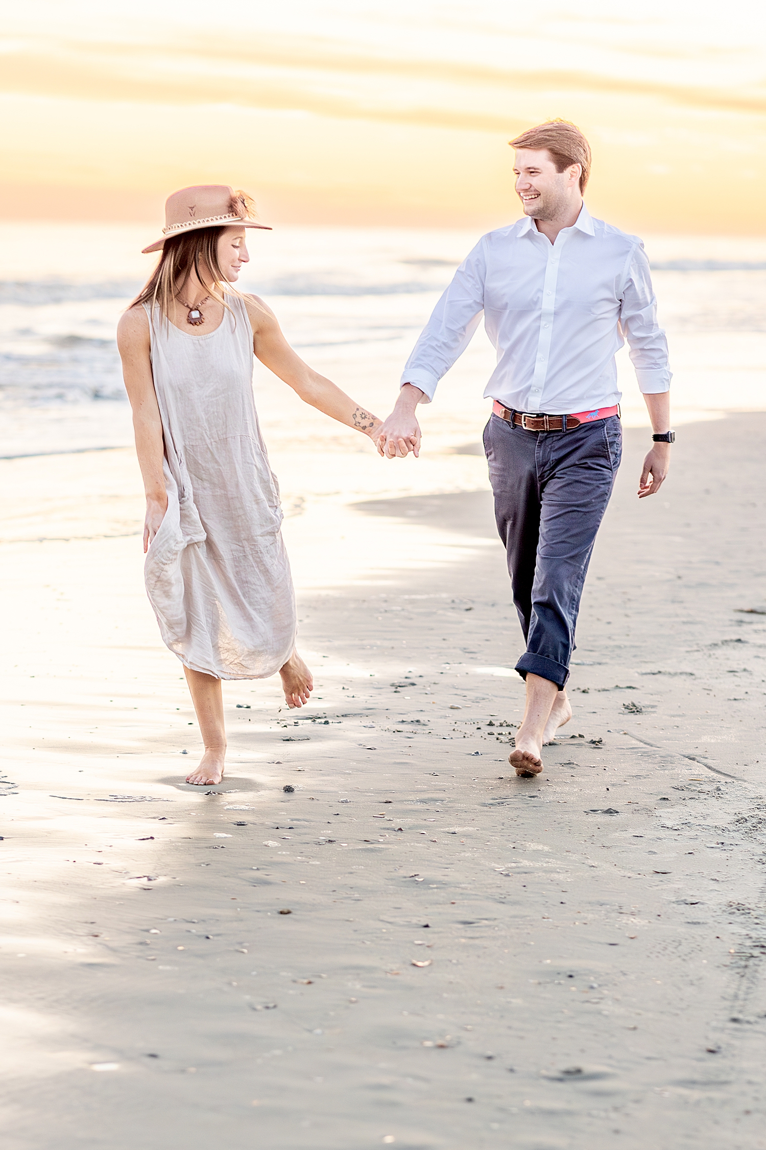 engaged couple hold hands as they walk together on the beach in SC