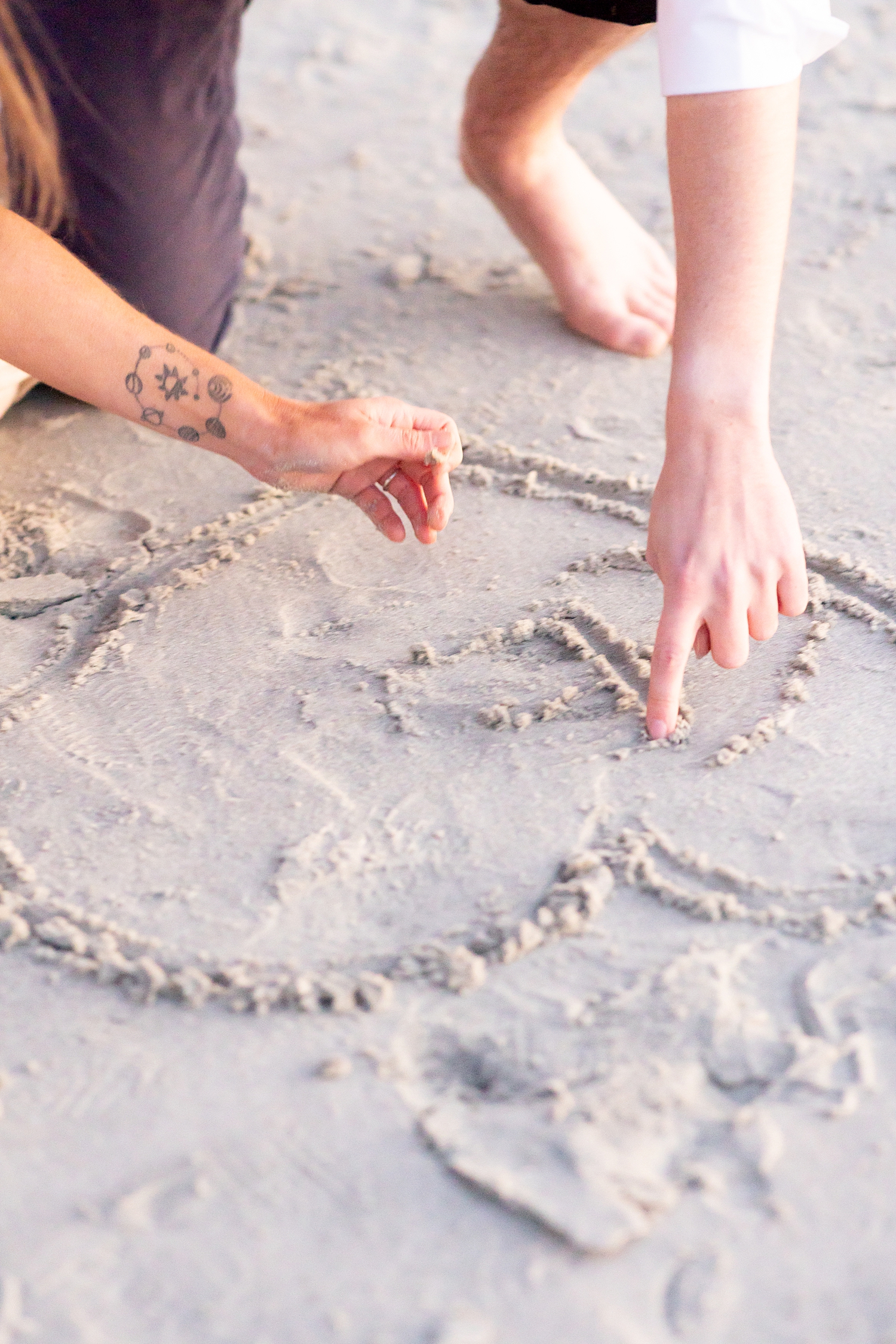 couple write their initials in the sand