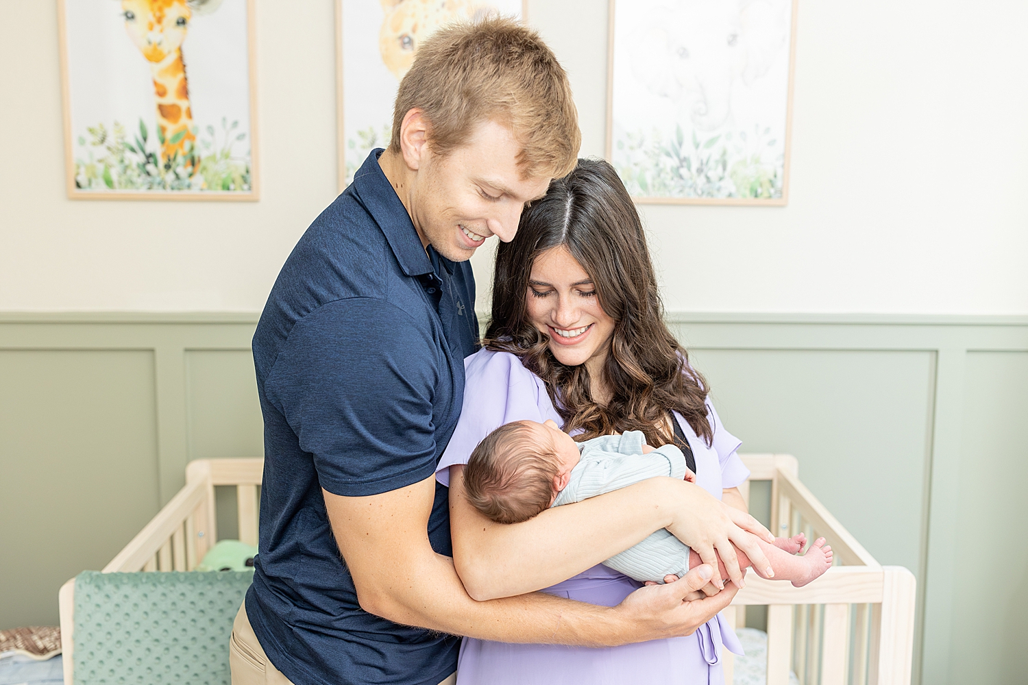 new parents look down lovingly at their newborn