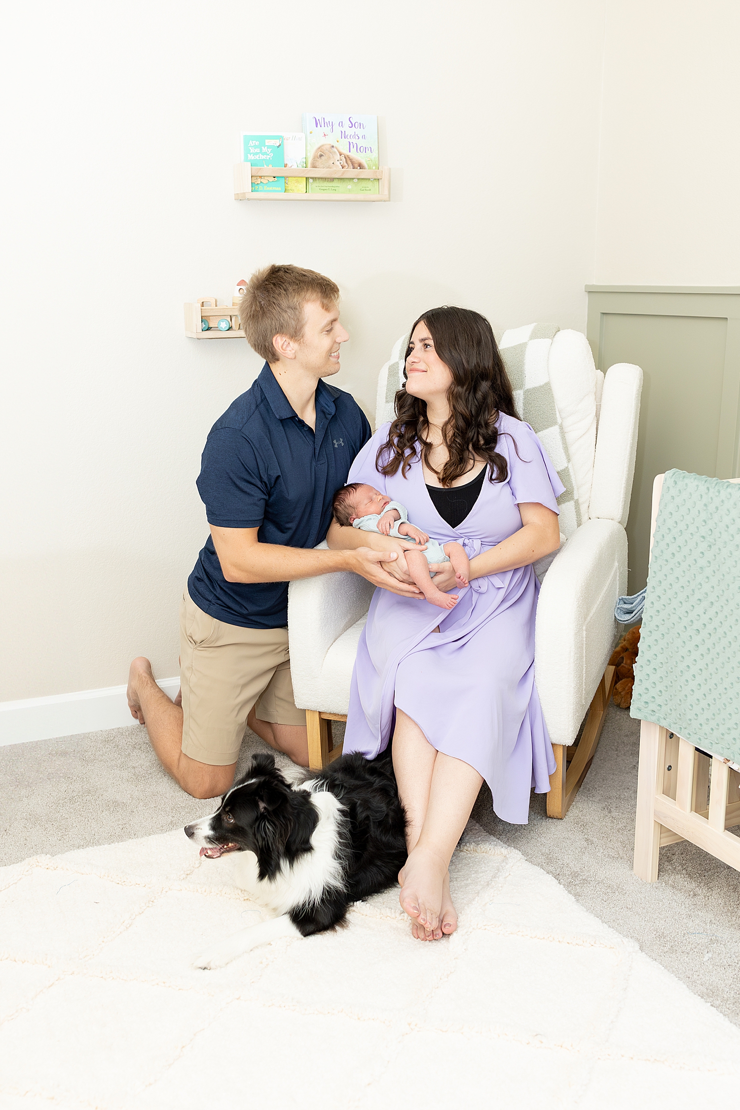 parents hold son in rocking chair as family dog sits nearby