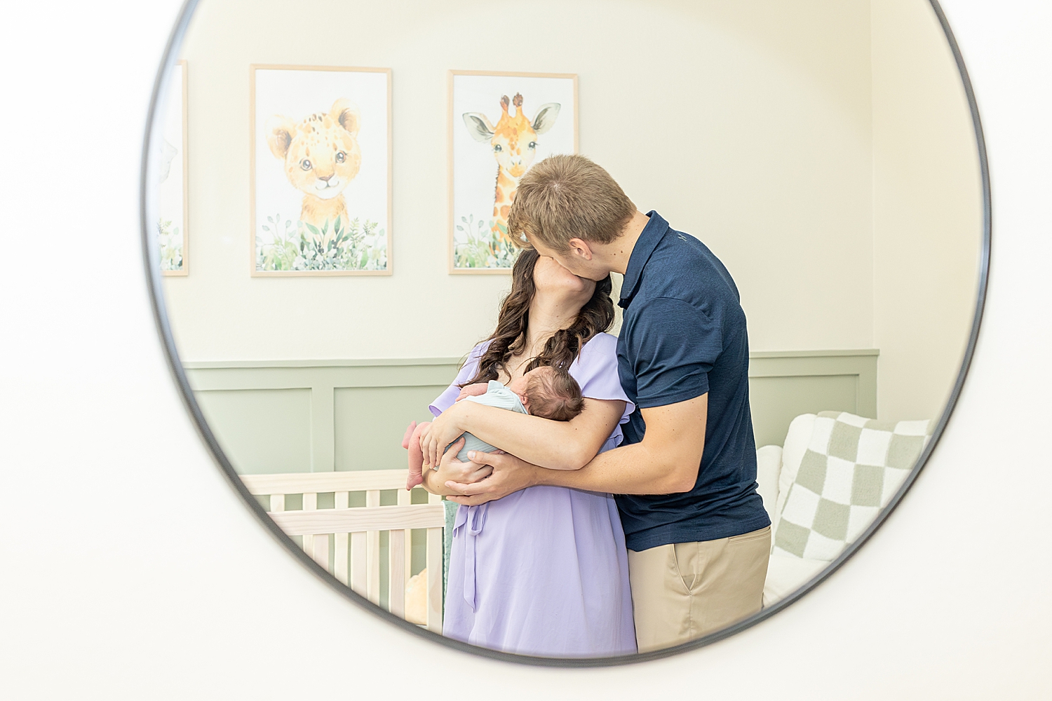 parents kiss as they hold newborn