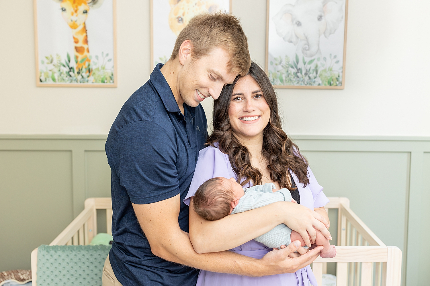 parents hold newborn by crib