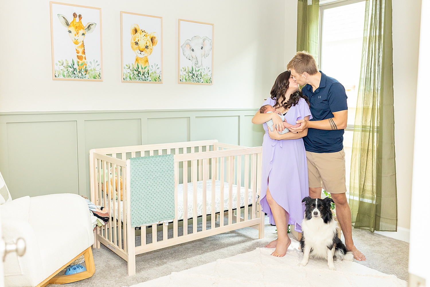 parents kiss as they hold newborn in nursery 