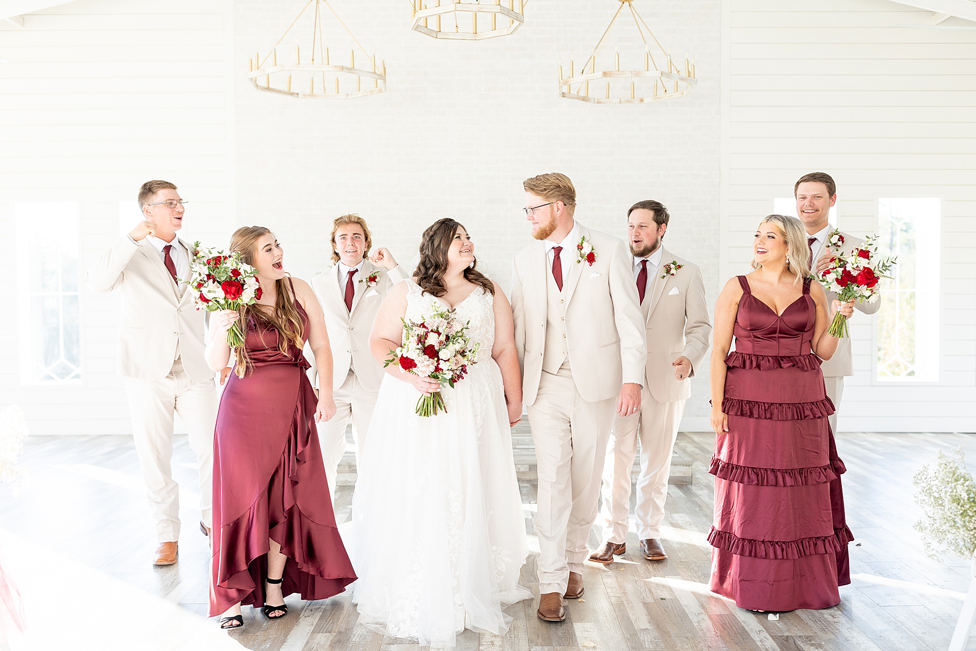 groomsmen in light tuxes and bridesmaids in dark red dresses 