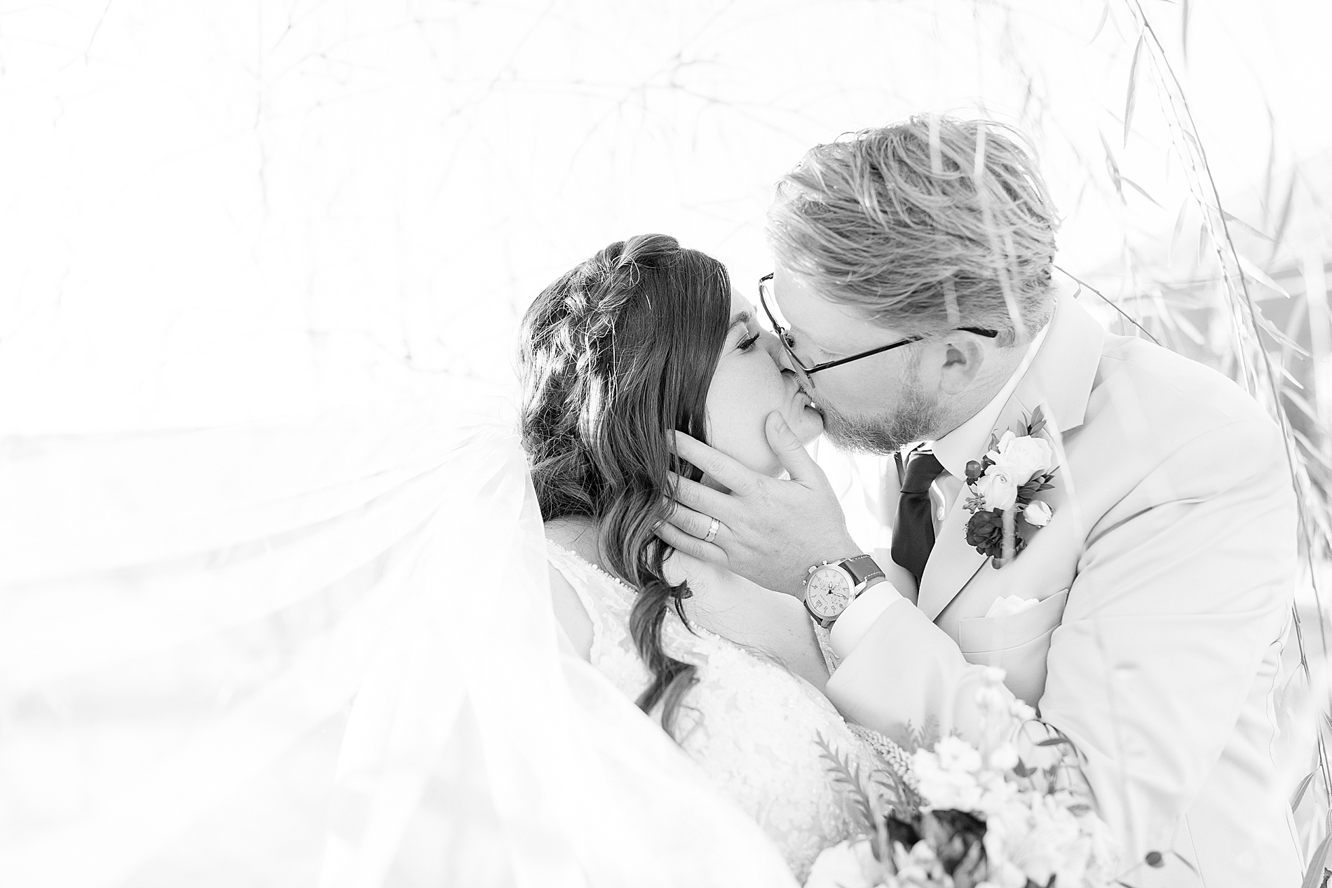 couple kiss surrounded by bride's veil