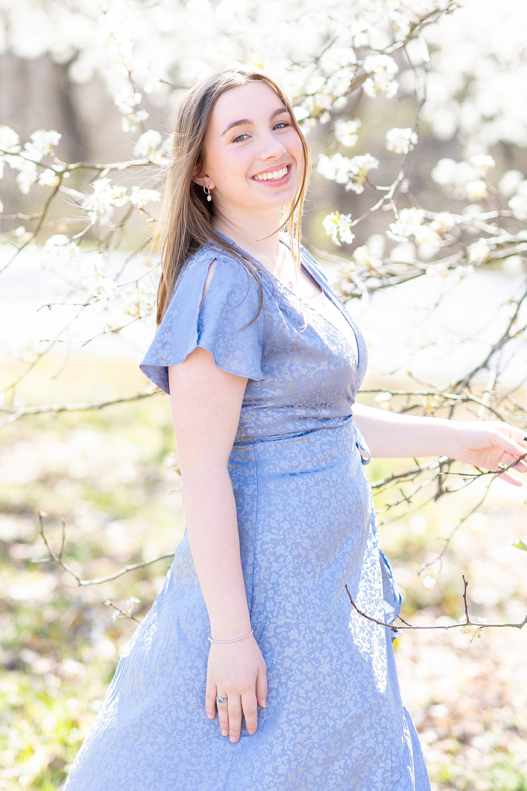 senior girl by white cherry blossom tree