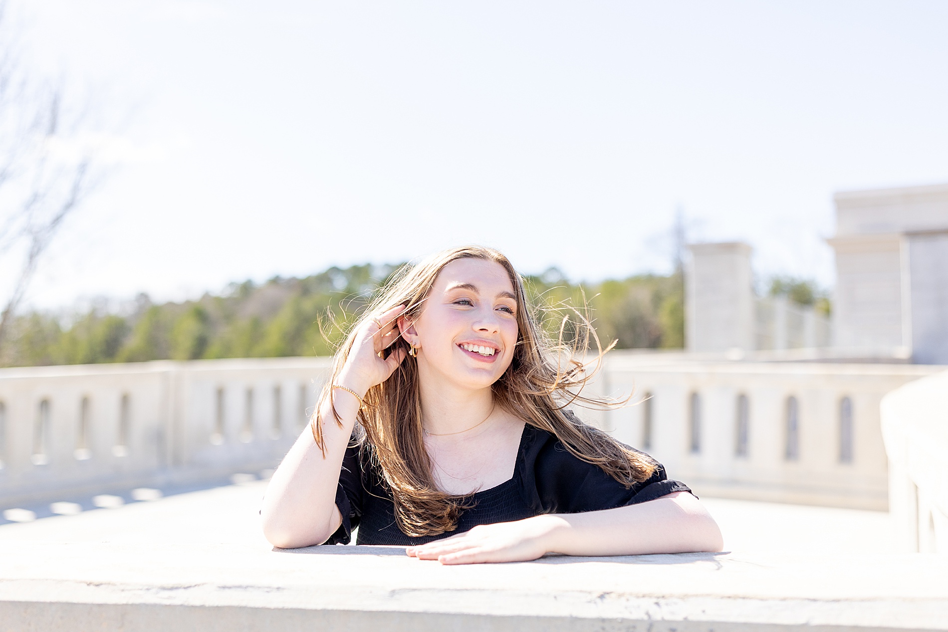 senior leans on ledge during senior photos