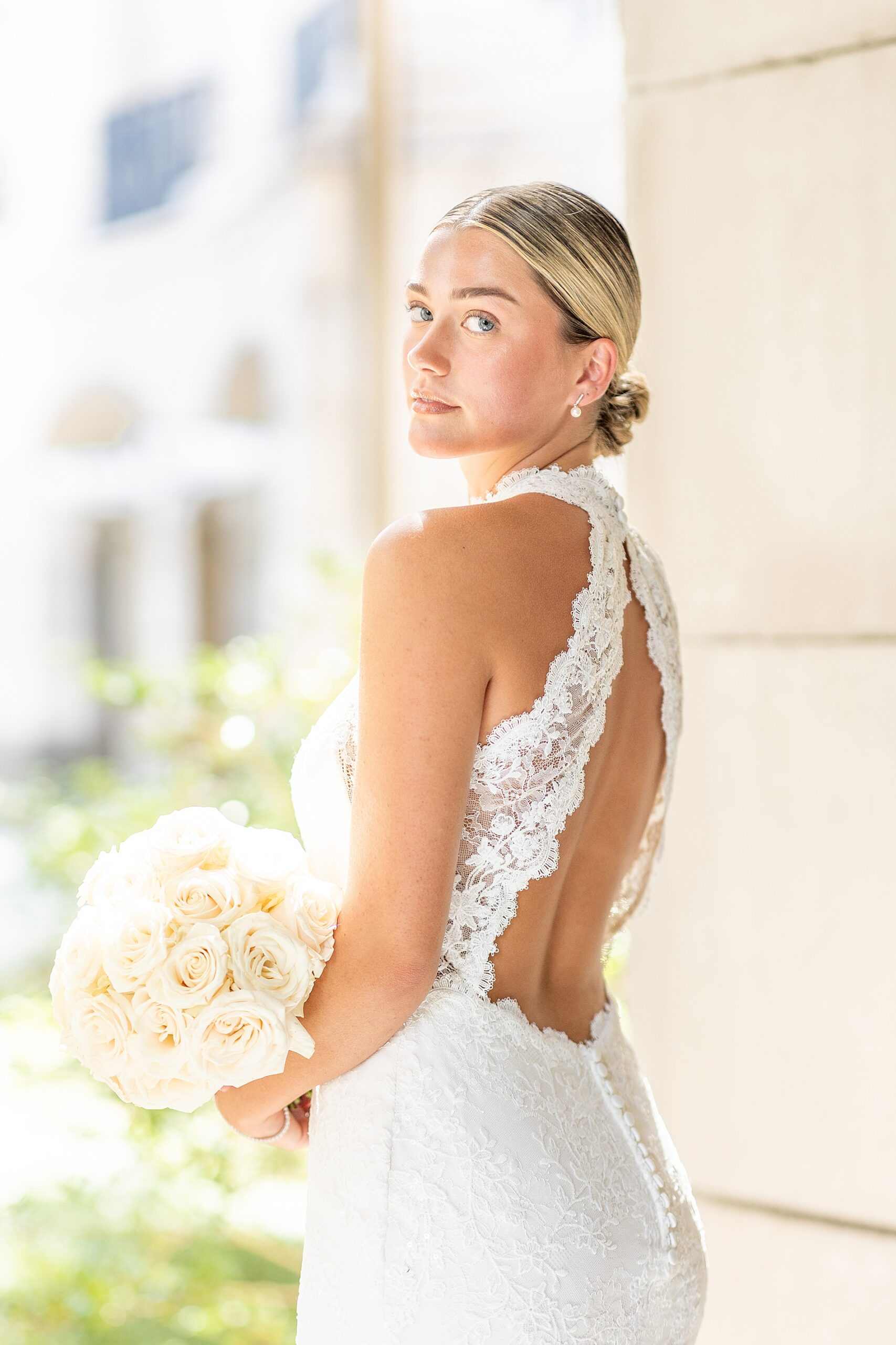 bride holds white bouquet in open back wedding dress