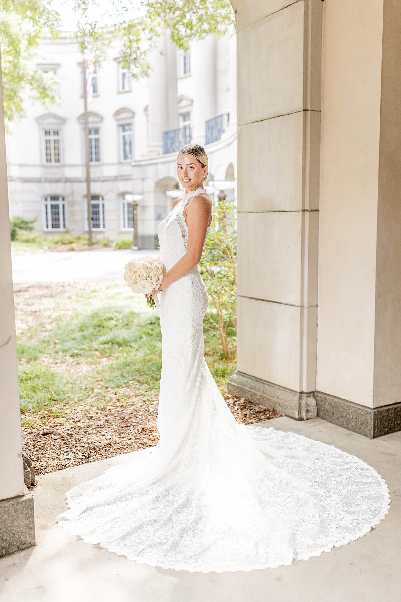 bride stands holding bouquet with wedding dress fanned out around her