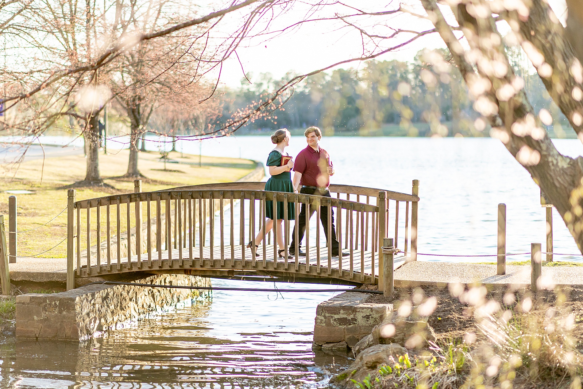 couple walk across wooden bridge over water