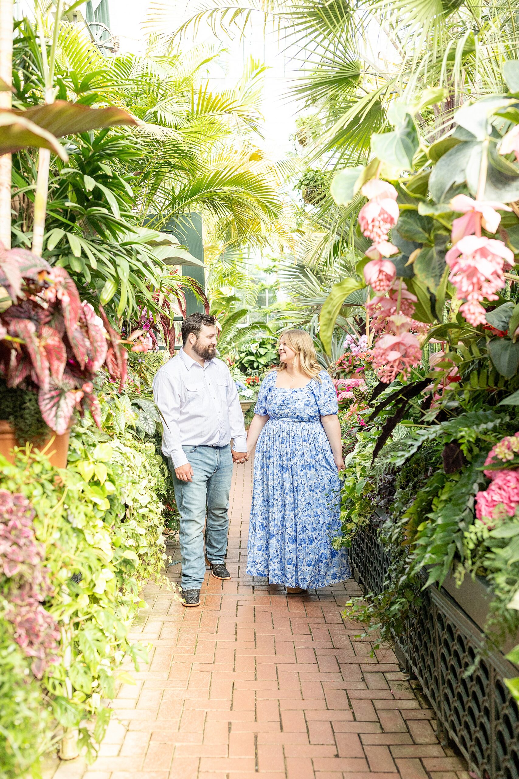 couple walk down path inside garden during Ashville NC engagement session