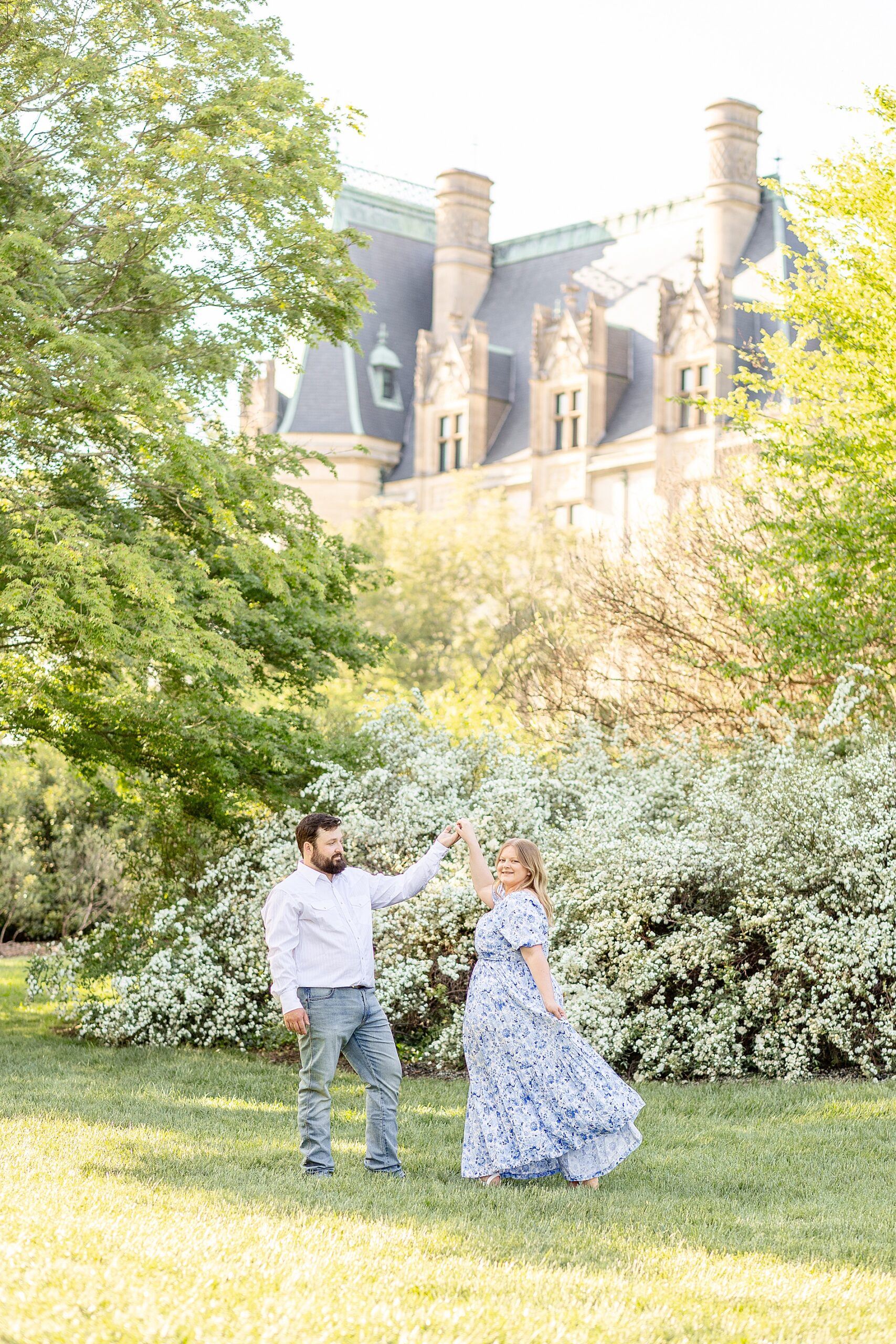 couple dance by blooming flowers during spring engagement
